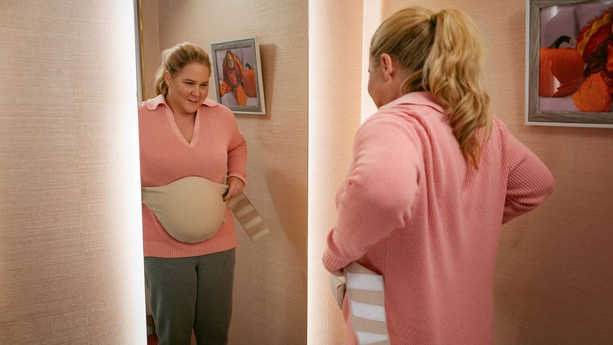 Lainy (Amy Schumer) holds up a fake baby bump to her body in Netflix's "Kinda Pregnant"