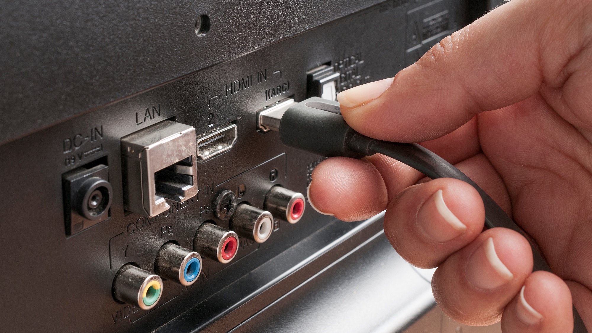 אישה מחברת כבל HDMI לטלוויזיה