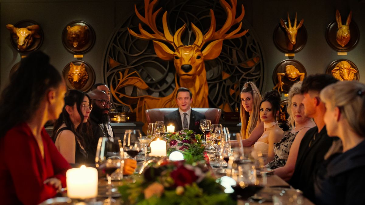 "Million Dollar Secret" contestants and host Peter Serafinowicz seated at a dining table in a still from the Netflix reality show.