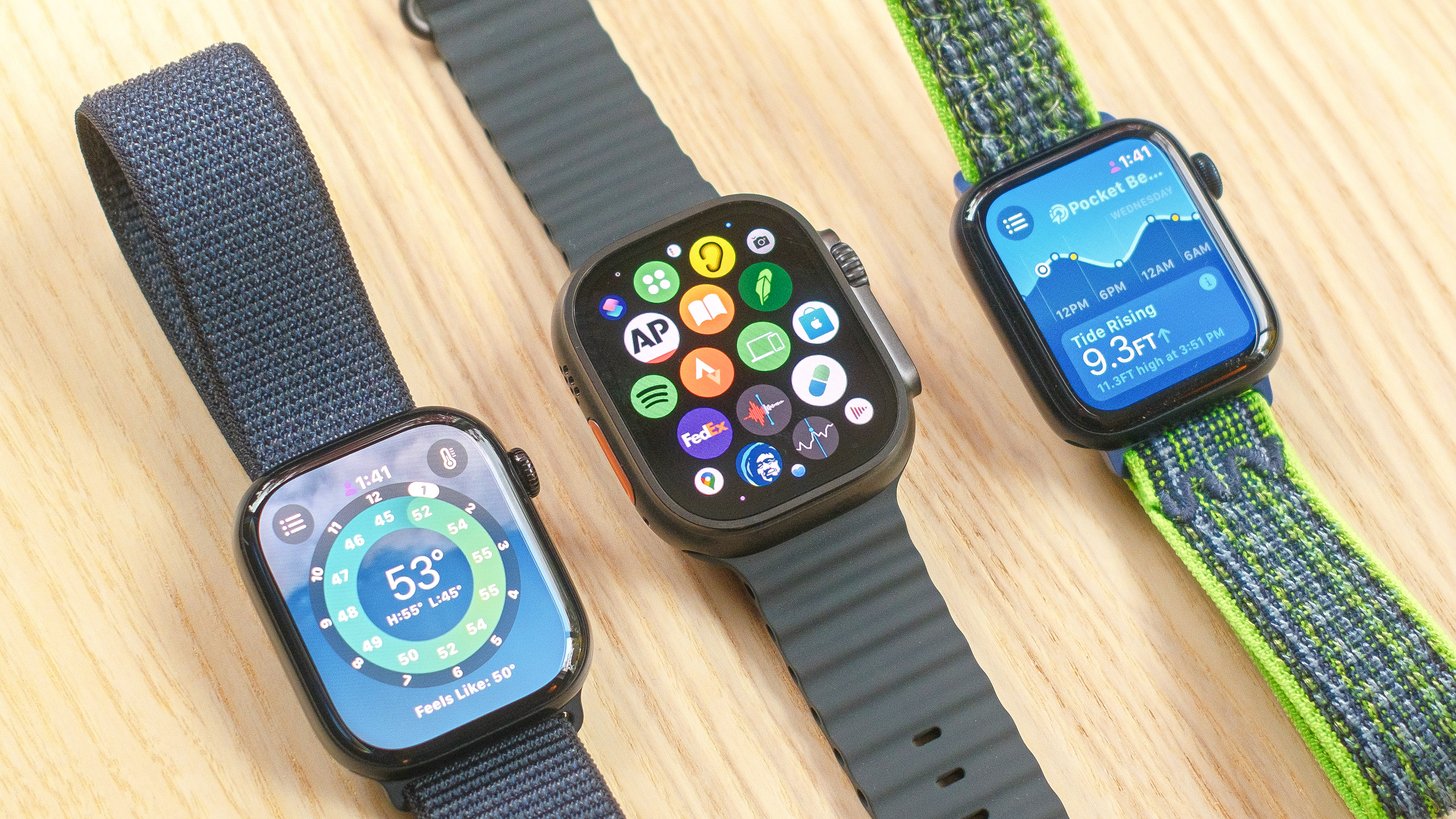 סדרת Apple Watch 10, Apple Watch SE ו- Apple Watch Ultra 2 יושבים אחד ליד השני על שולחן עץ