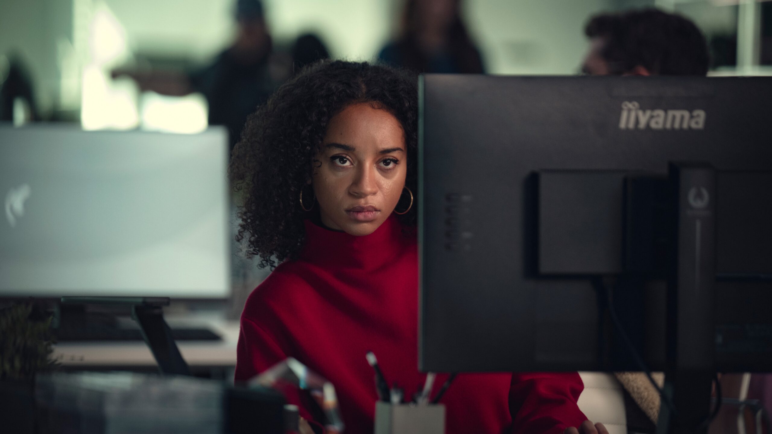 Maria (Siena Kelly) leans around a computer monitor in a scene from the "Black Mirror" season 7 episode, "Bête Noire."