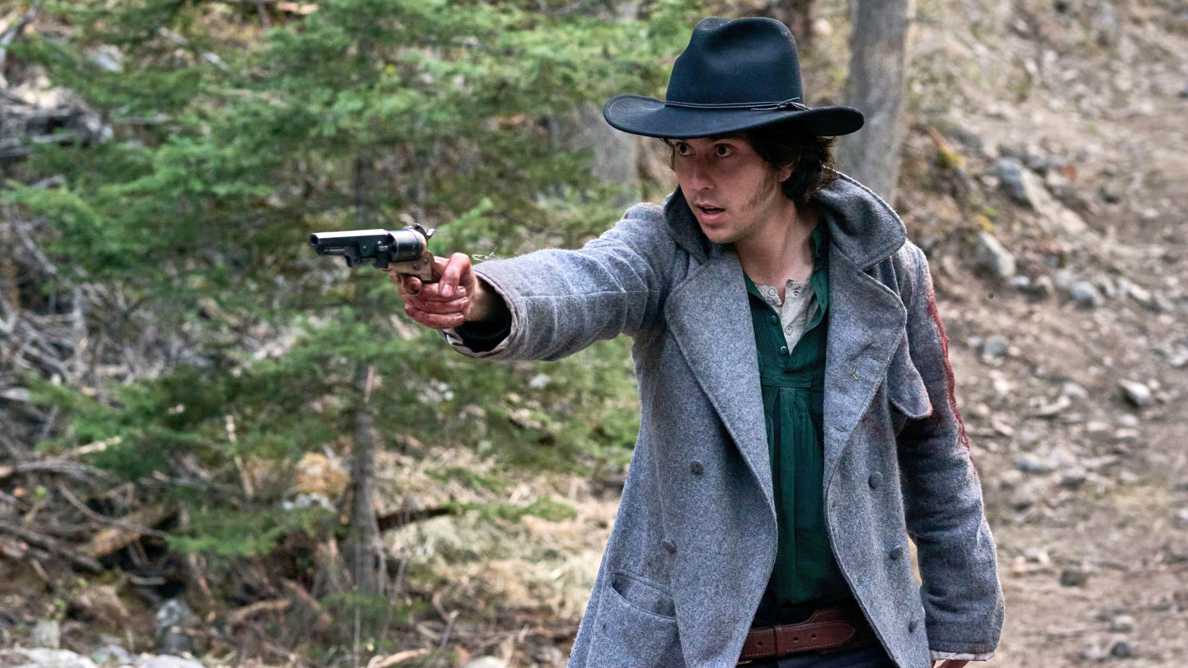 ג'ימי אמברוז ג'וניור (נט וולף) במאגר אפור וכובע אוחז באקדח בסצנה מ 