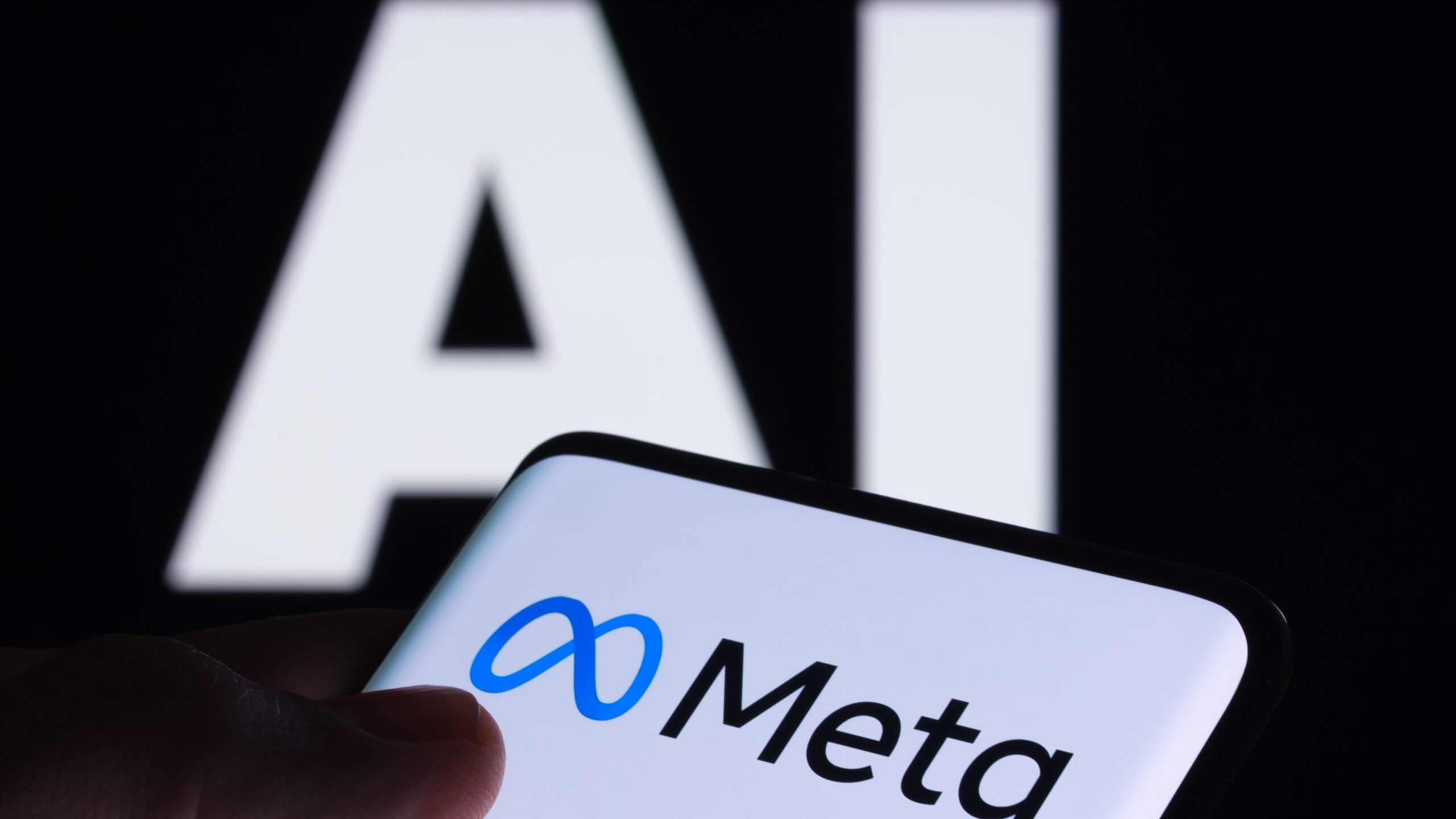 A mobile device displaying the Meta logo in front of large letters spelling out 'AI'