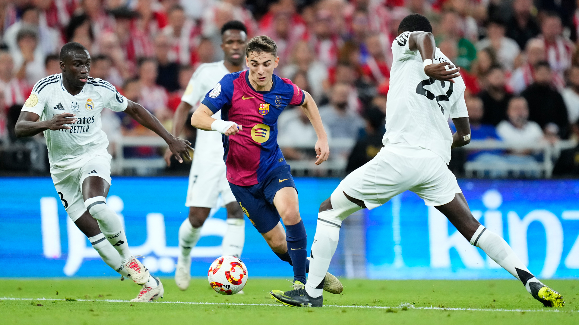 Gavi of Barcelona runs with the ball, evading the attention of three Real Madrid players during the January 2025 Spanish Super Cup final