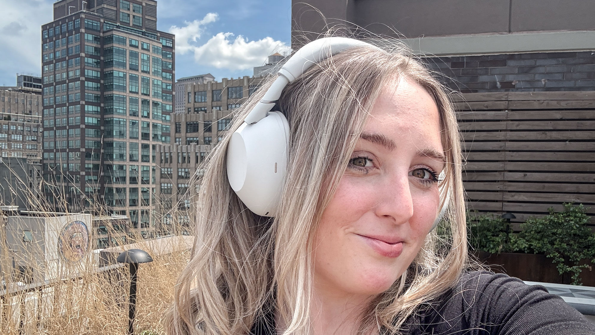 אישה עונדת אוזניות לבנות מסוג Sony WH-1000XM6 ביטול רעשים