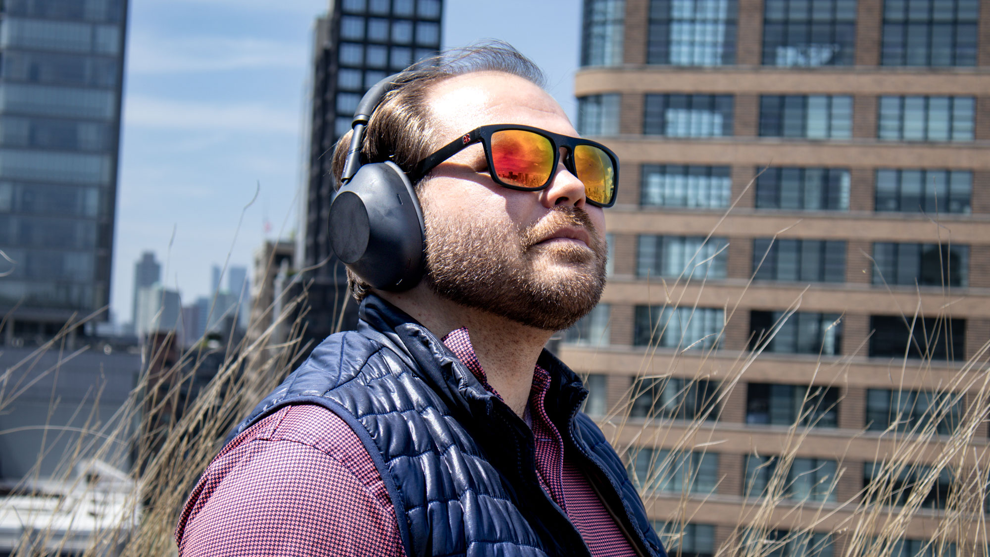 גבר לובש אוזניות שחורות של Sony WH-1000XM6 מבטל רעשים עם משקפי שמש