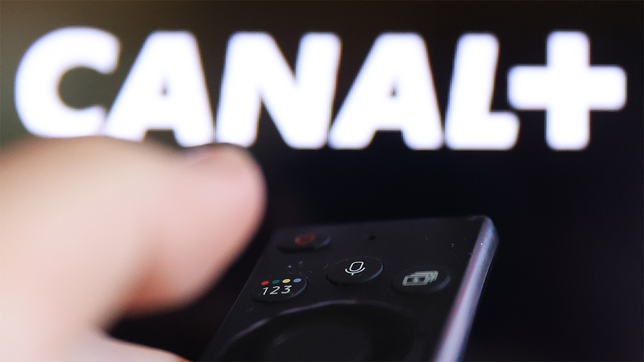 White Canal+ logo displayed on screen, while person points a streaming remote towards it