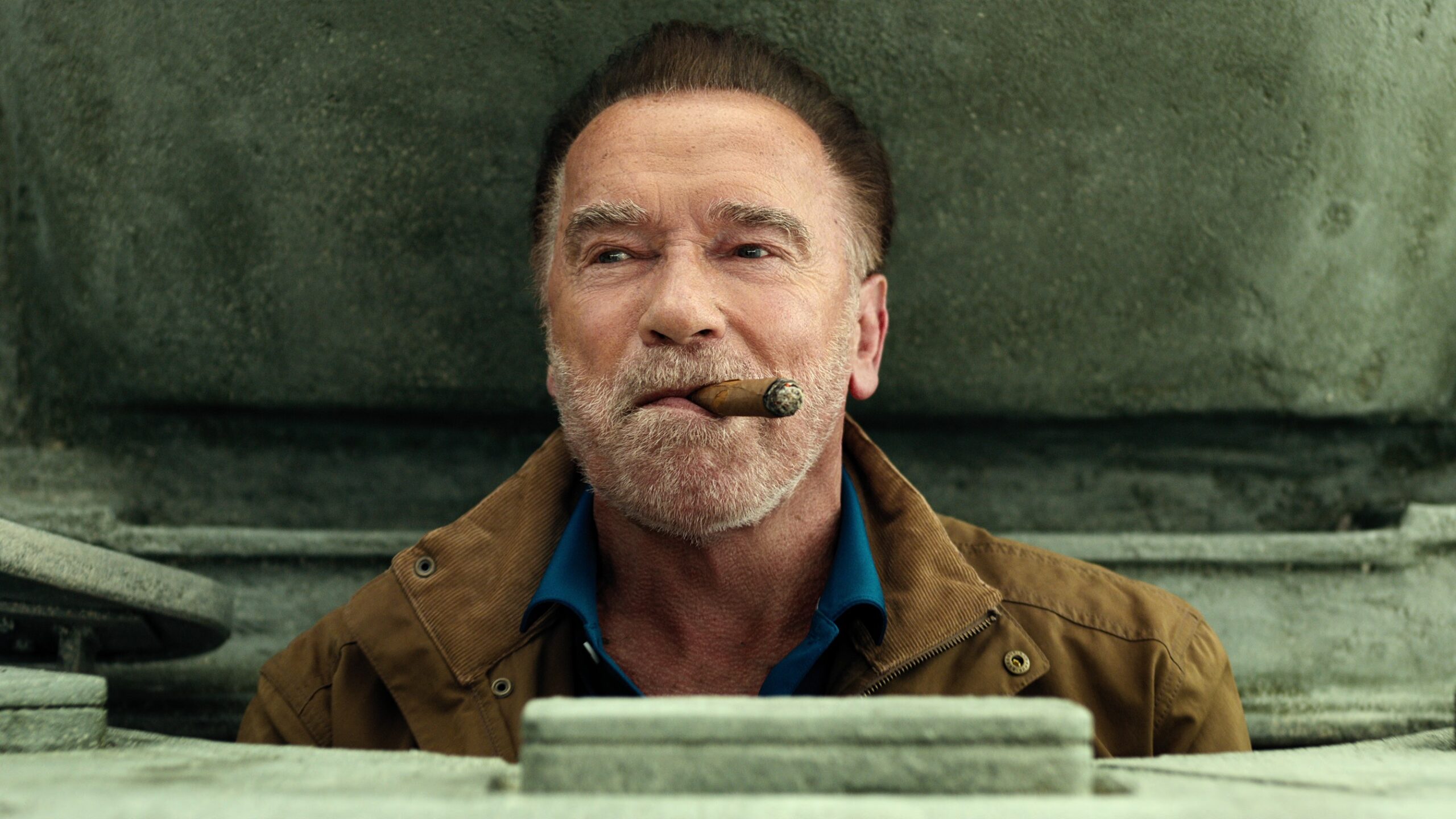 Luke Brunner (Arnold Schwarzenegger) pops out of a tank hatch smoking a cigar in a scene from Netflix's "FUBAR" season 2