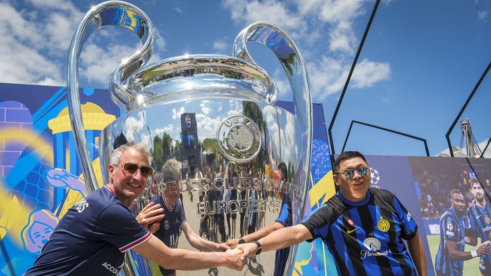 An Inter and a PSG fan posing with a giant trophy ahead of the 2025 Champions League final in Munich, Germany on May 29, 2025.