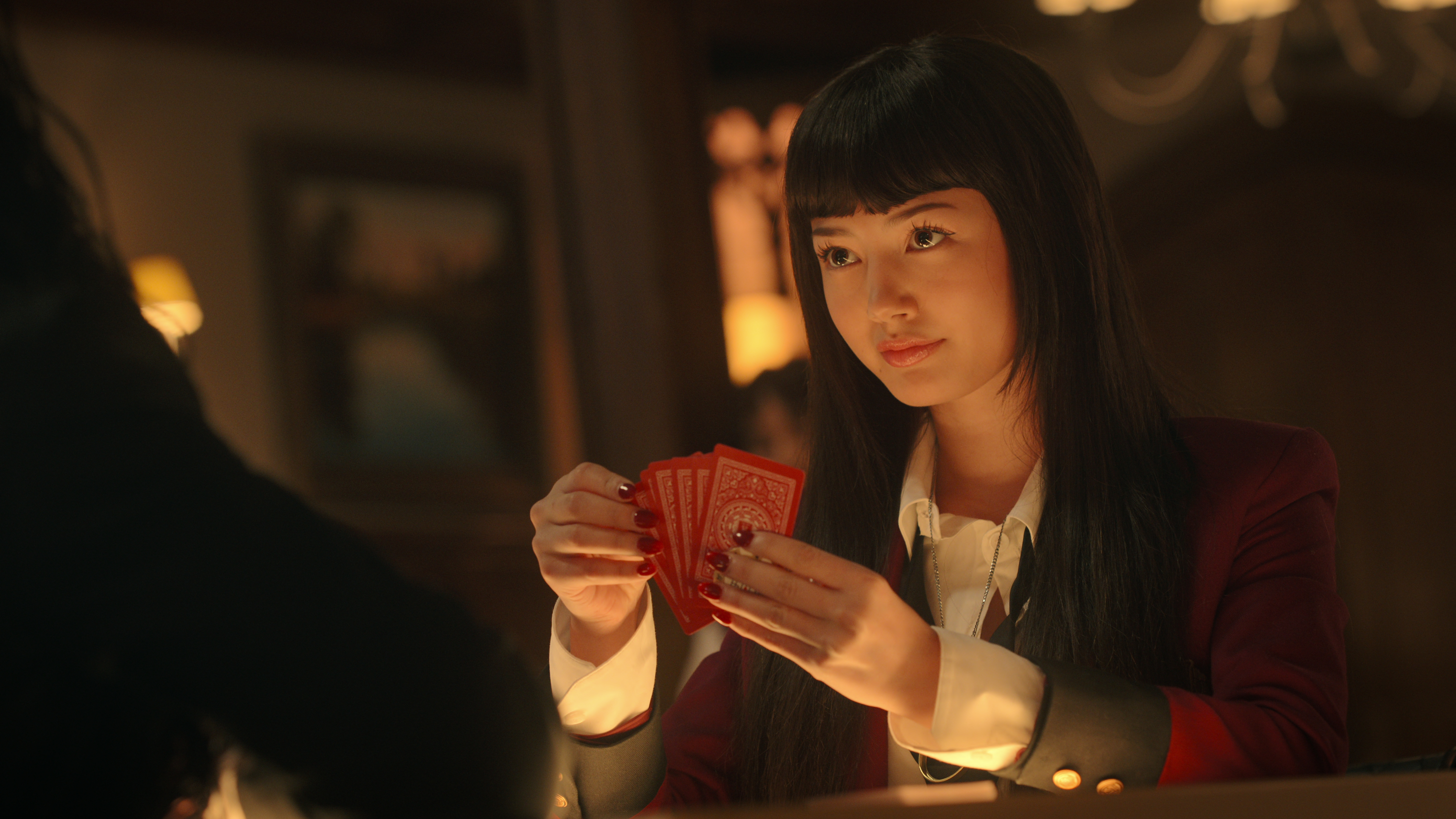 Yumeko (מיקו מרטינו) עם כרטיסים ביד בסצנה של נטפליקס "Kakegurui" הִסתַגְלוּת, "לְהִתְעַרֵב"