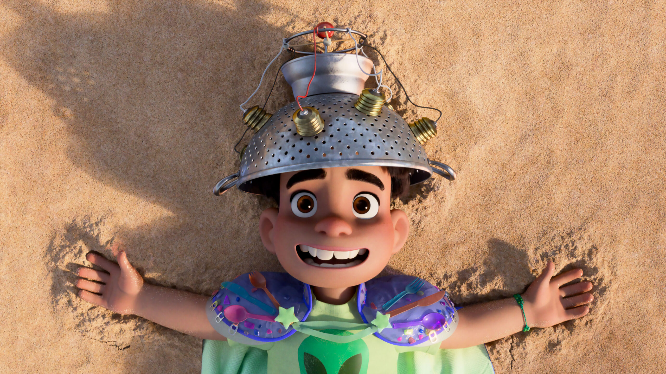 Elio lies on a beach in his cap and collander hat in a scene from "Elio"