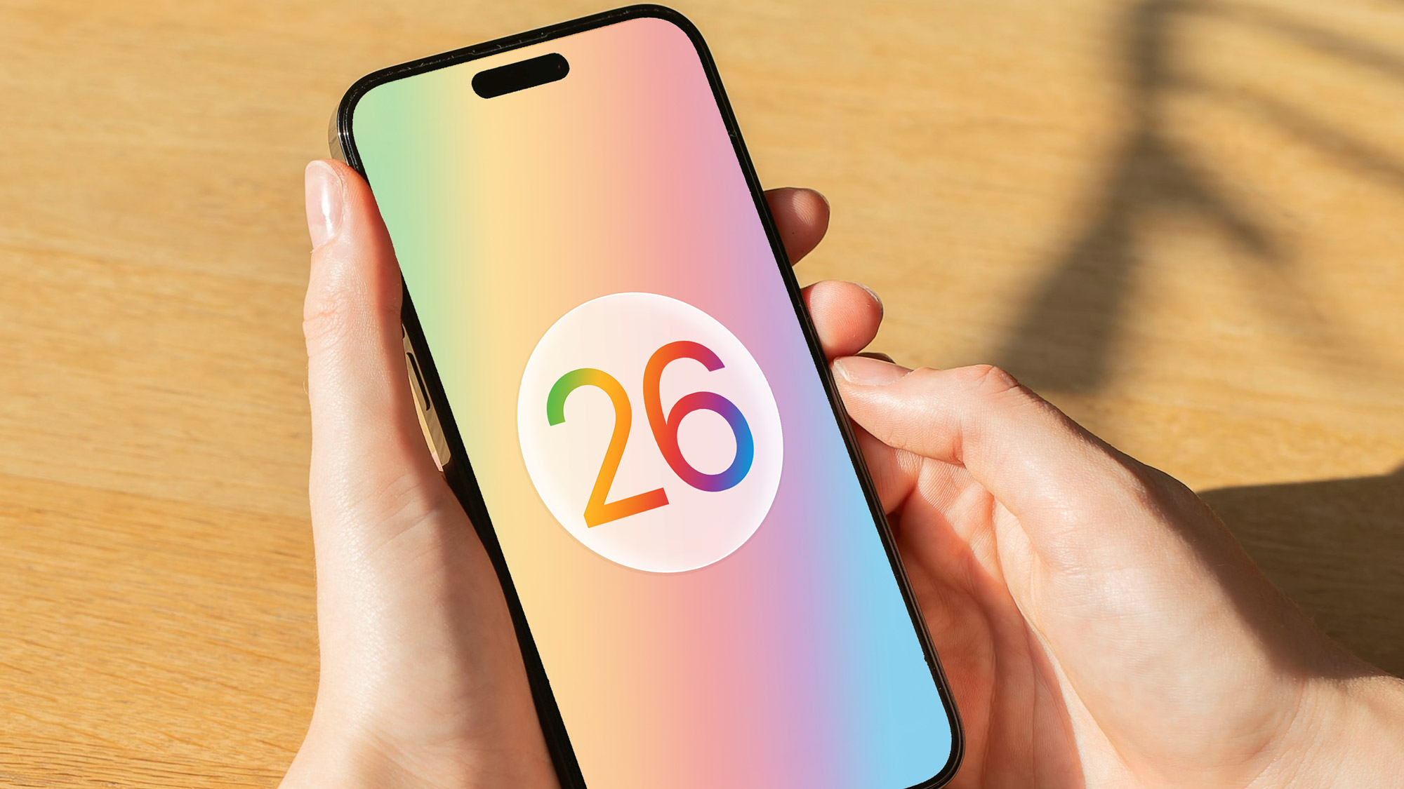 עיבוד של הלוגו של Apple iOS 26 באייפון המוחזק ביד.