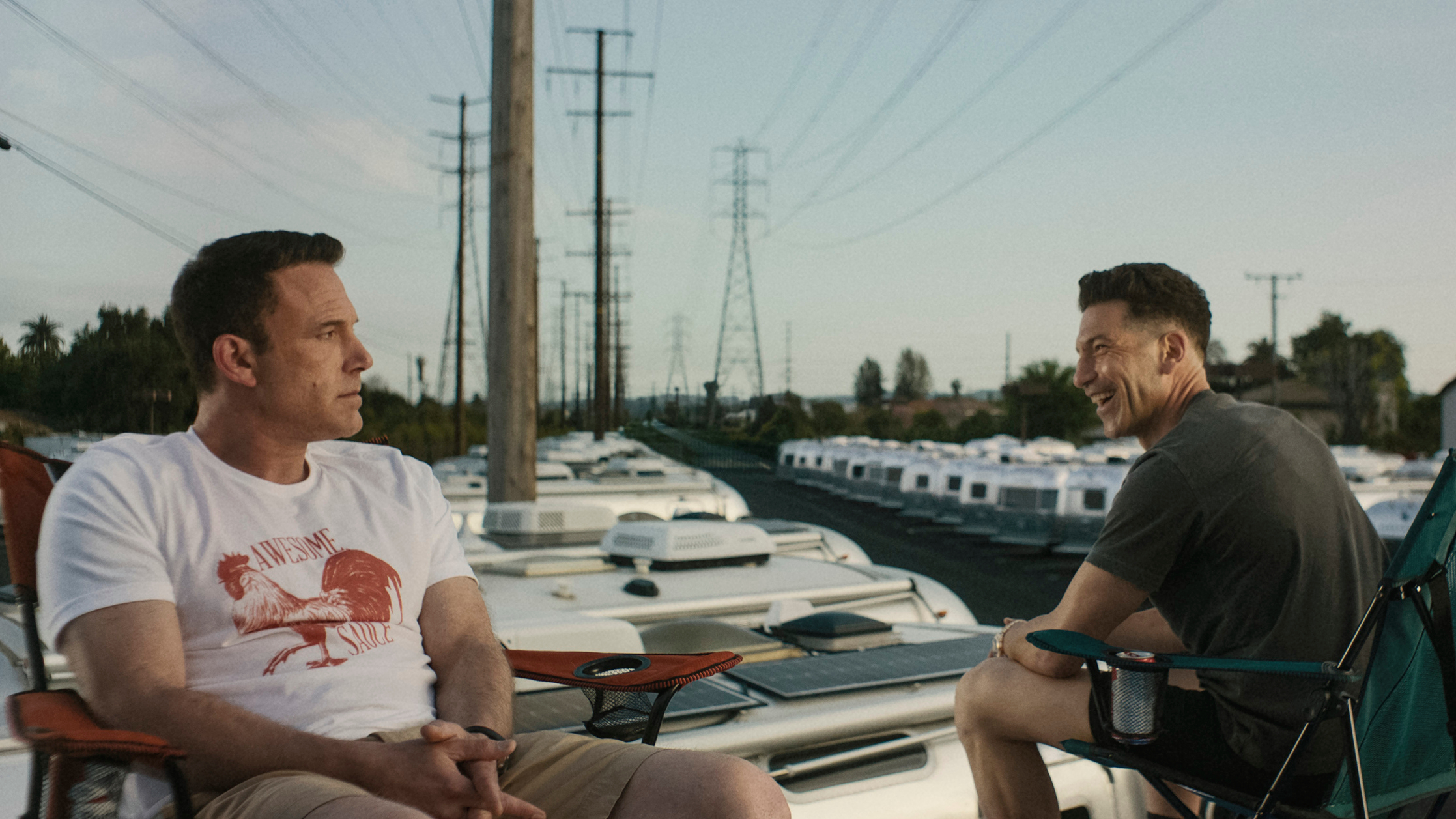 L-R: Christian Wolff (Ben Affleck) and Brax (Jon Bernthal) sit on folding chairs in a scene from "The Accountant 2"