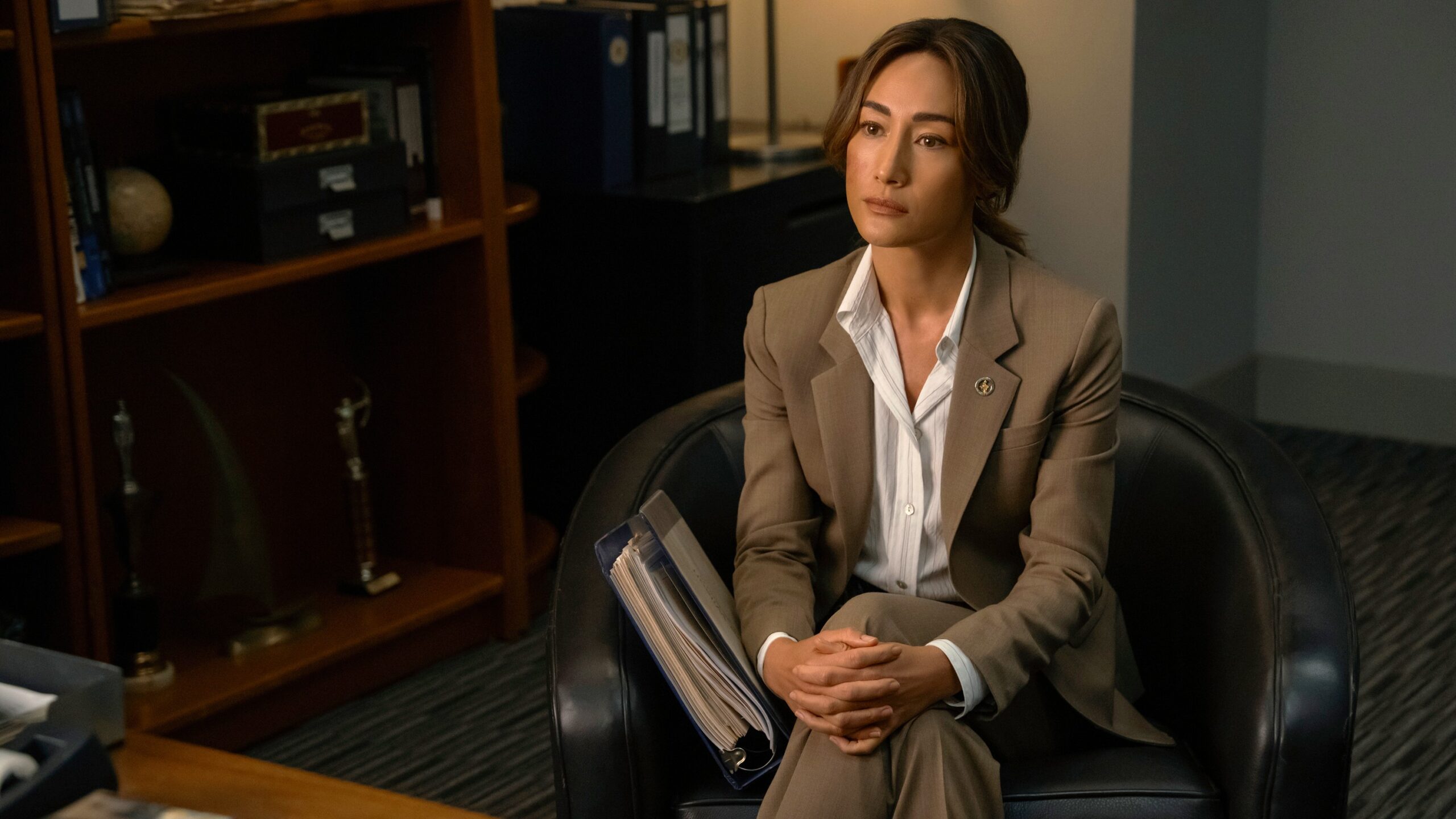 Renée Ballard (Maggie Q) sits cross-legged in an armchair in an office in a scene from Prime Video