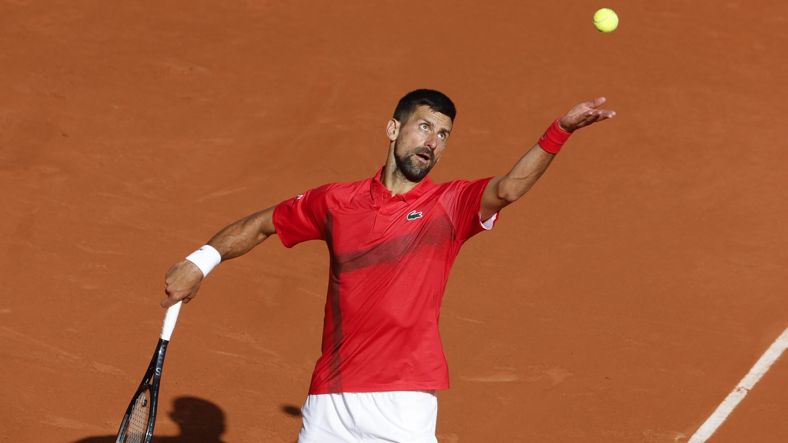 Novak Djokovic tosses his ball up for a serve at the 2025 French Open