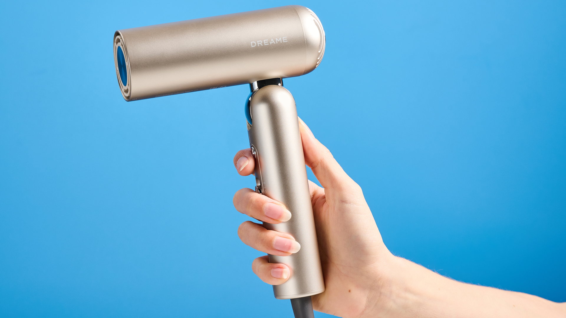 יד אוחזת ב-Dreame Pocket Neo בזהב מצולמת מול רקע כחול.