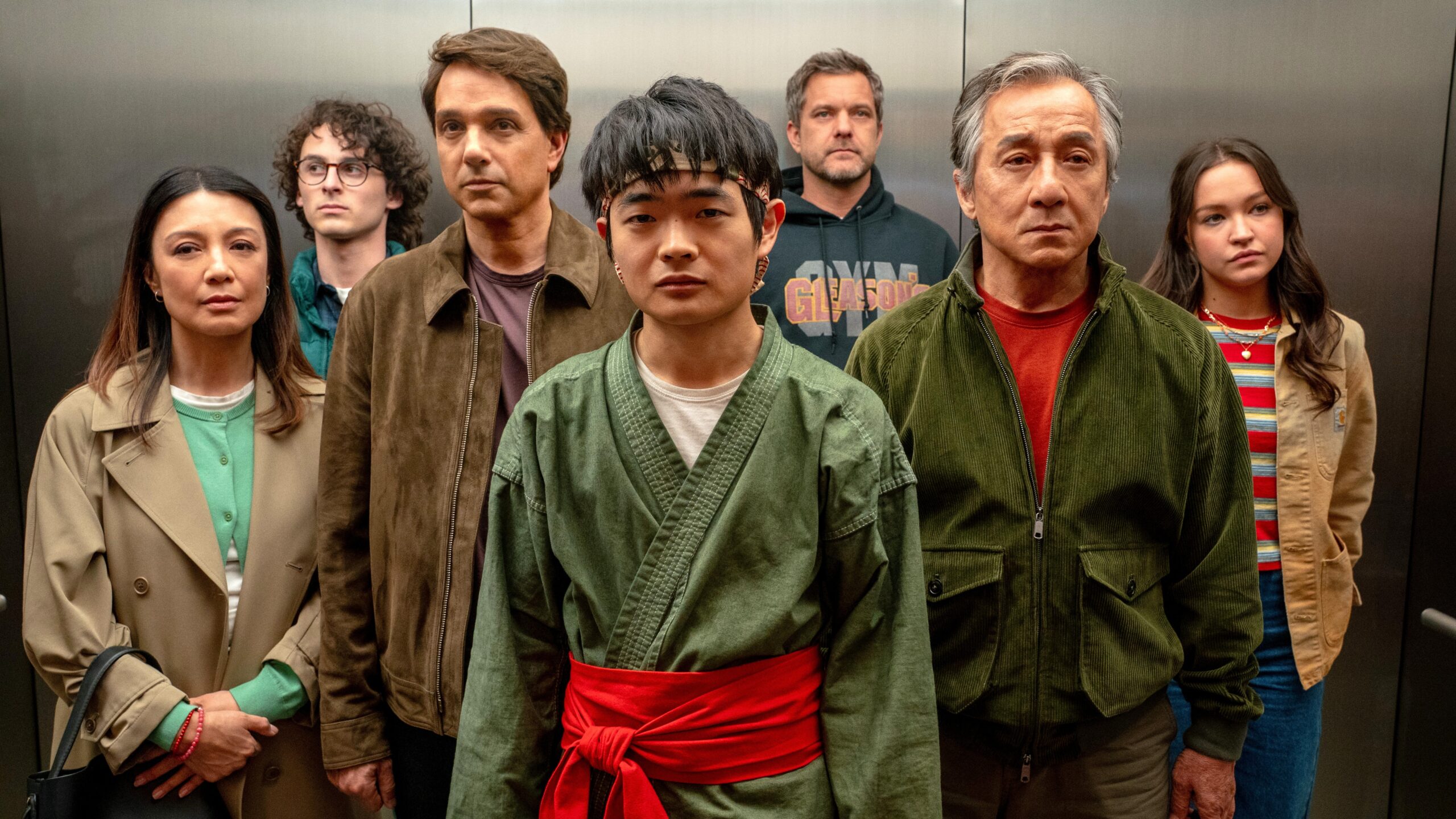 The "Karate Kid: Legends" main ensemble standing together in an elevator in a scene from the movie. L-R: Ming Na Wen, Wyatt Oleff, Ralph Macchio, Ben Wang, Joshua Jackson, Jackie Chan and Sadie Stanley