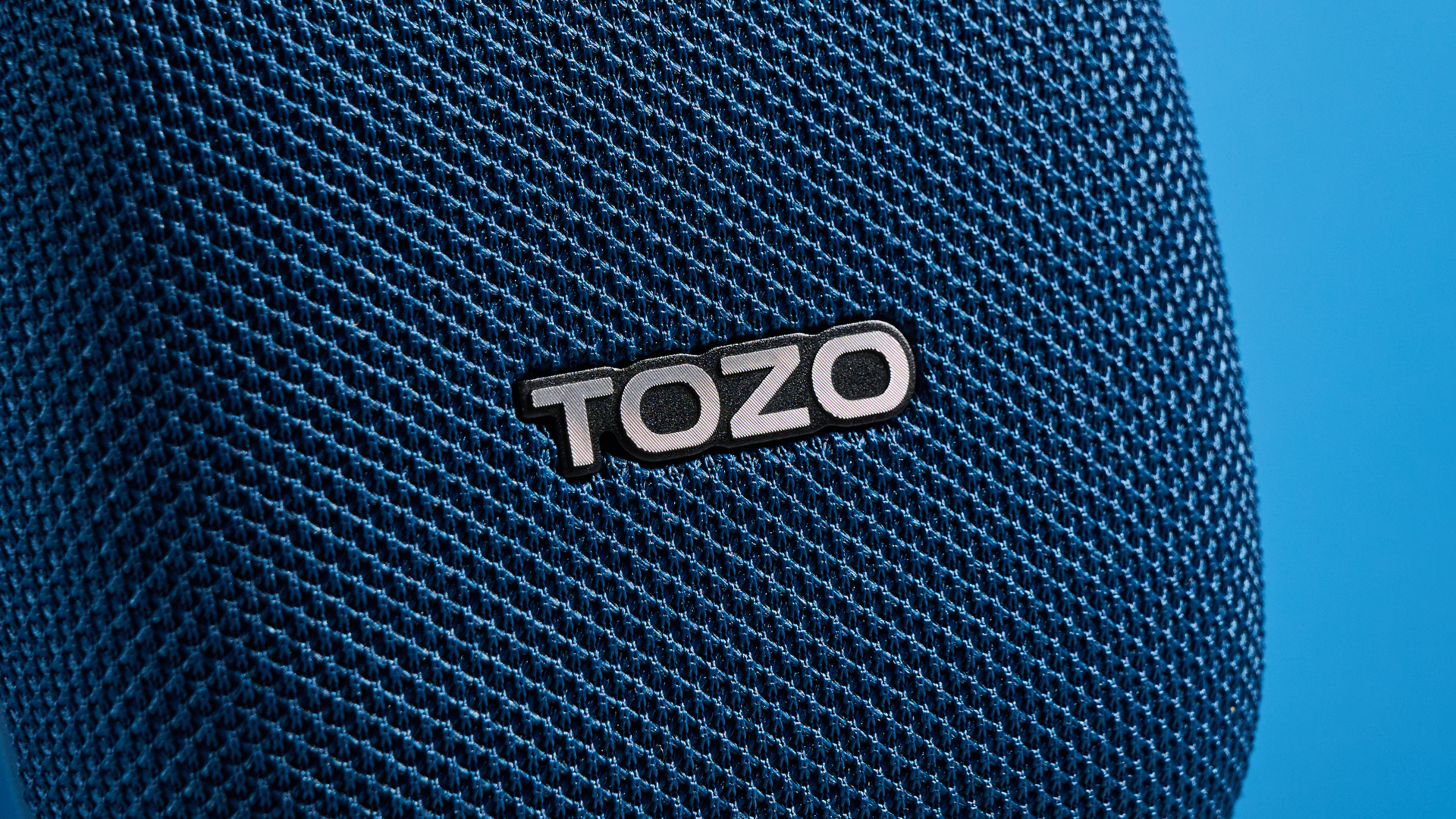 רמקול TOZO PE1 בכחול עם קליפ מובנה שצולם על רקע כחול.