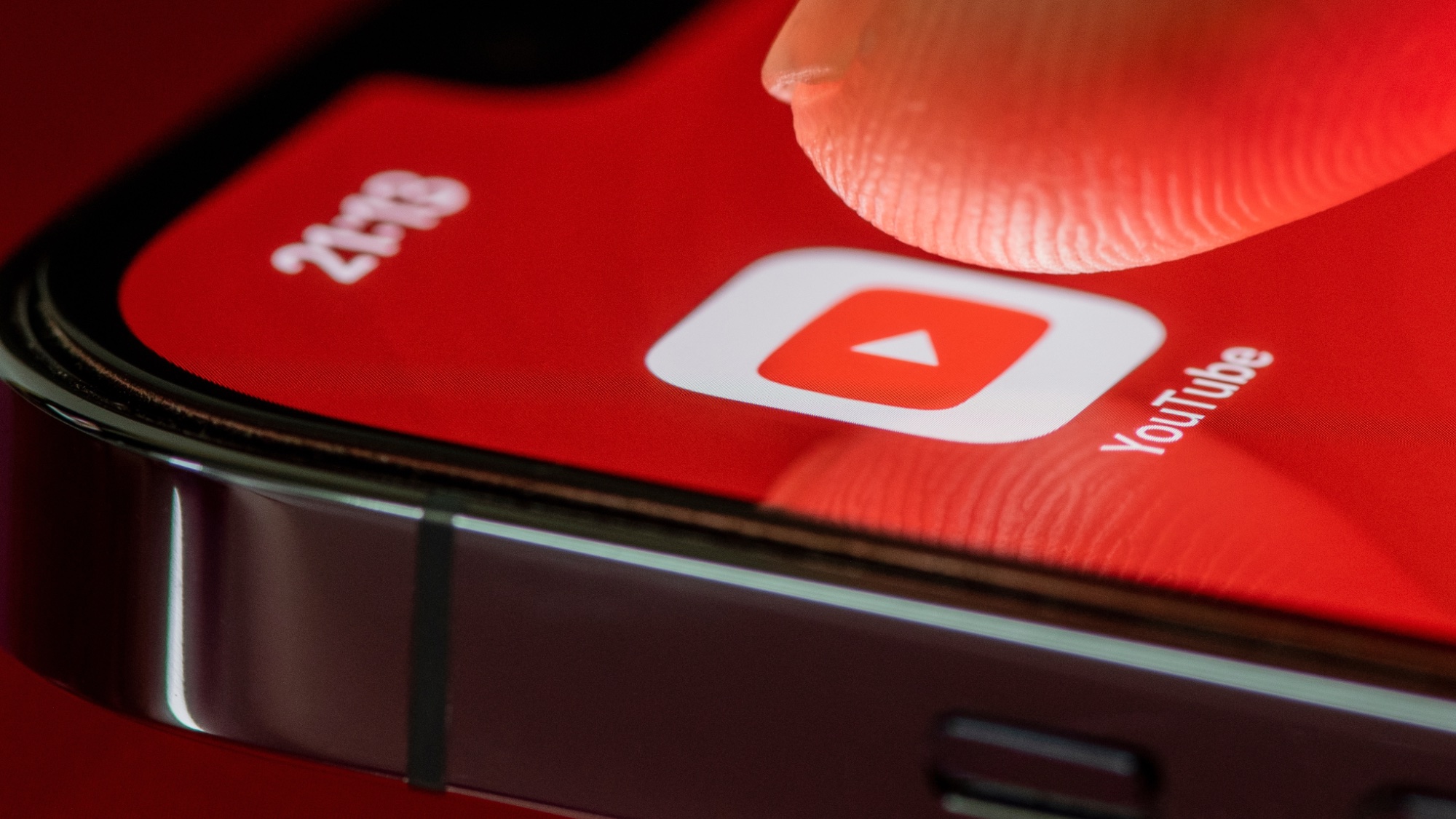 YouTube app icon on iPhone with finger