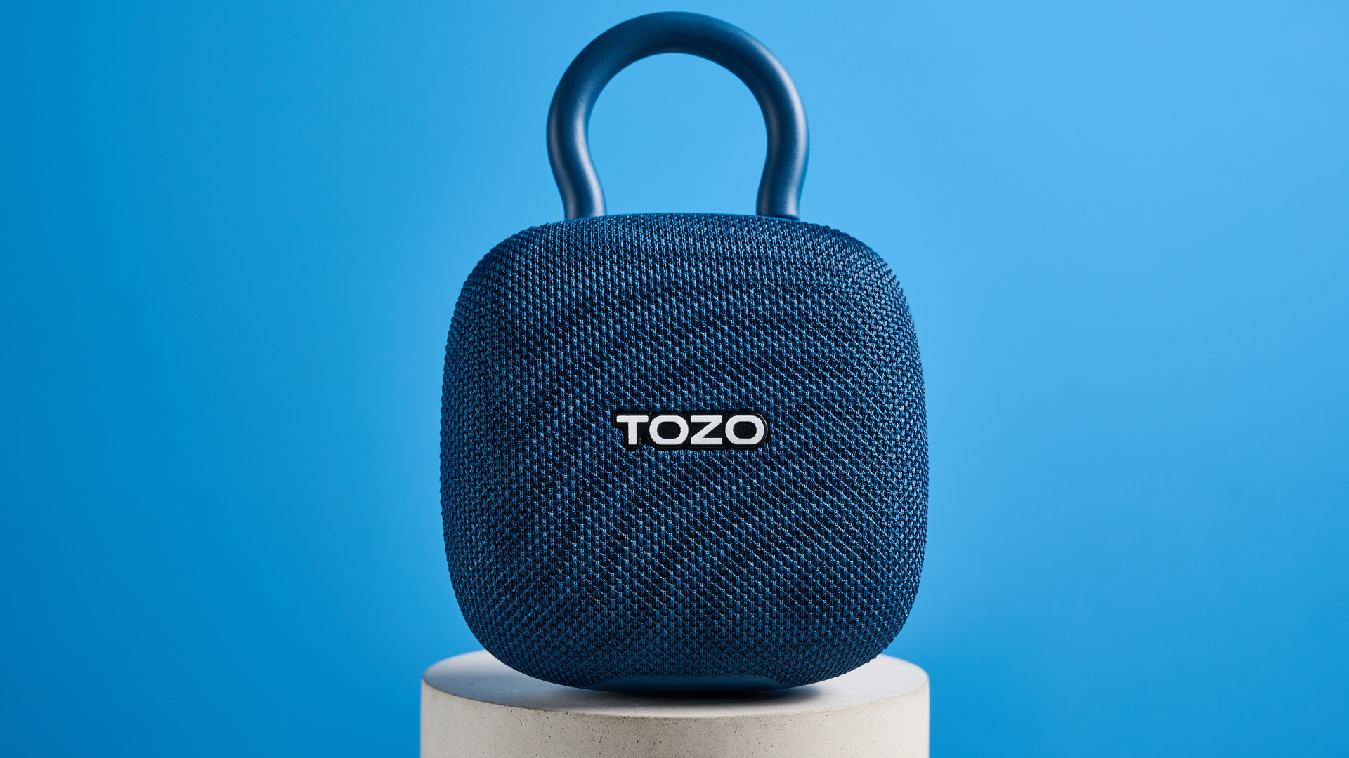 רמקול TOZO PE1 בכחול עם קליפ מובנה שצולם על רקע כחול.