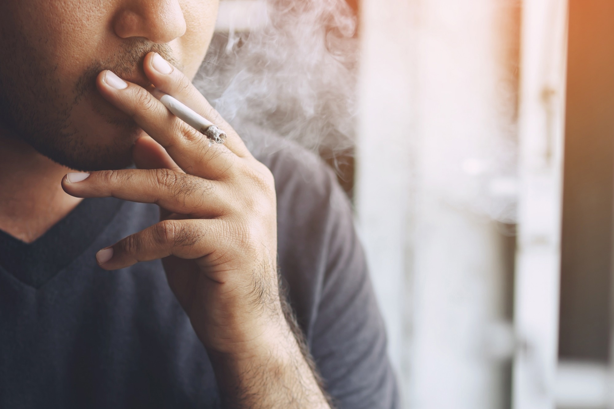 man holding smoking a cigarette in hand
