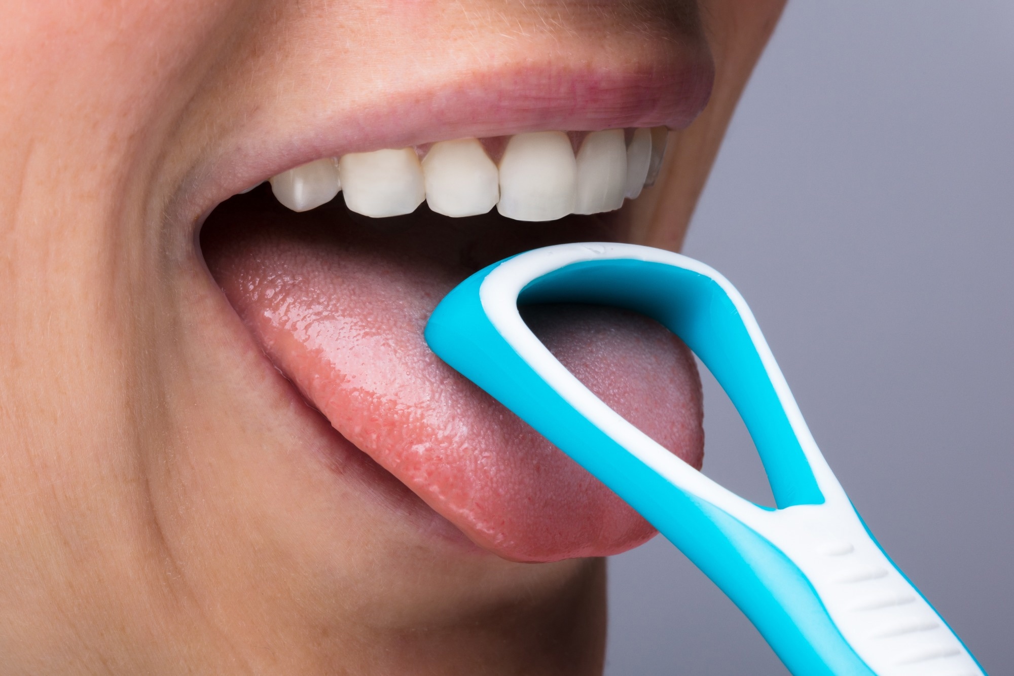 Close-up Of Young Woman Scraping Tongue With Plastic Tool
