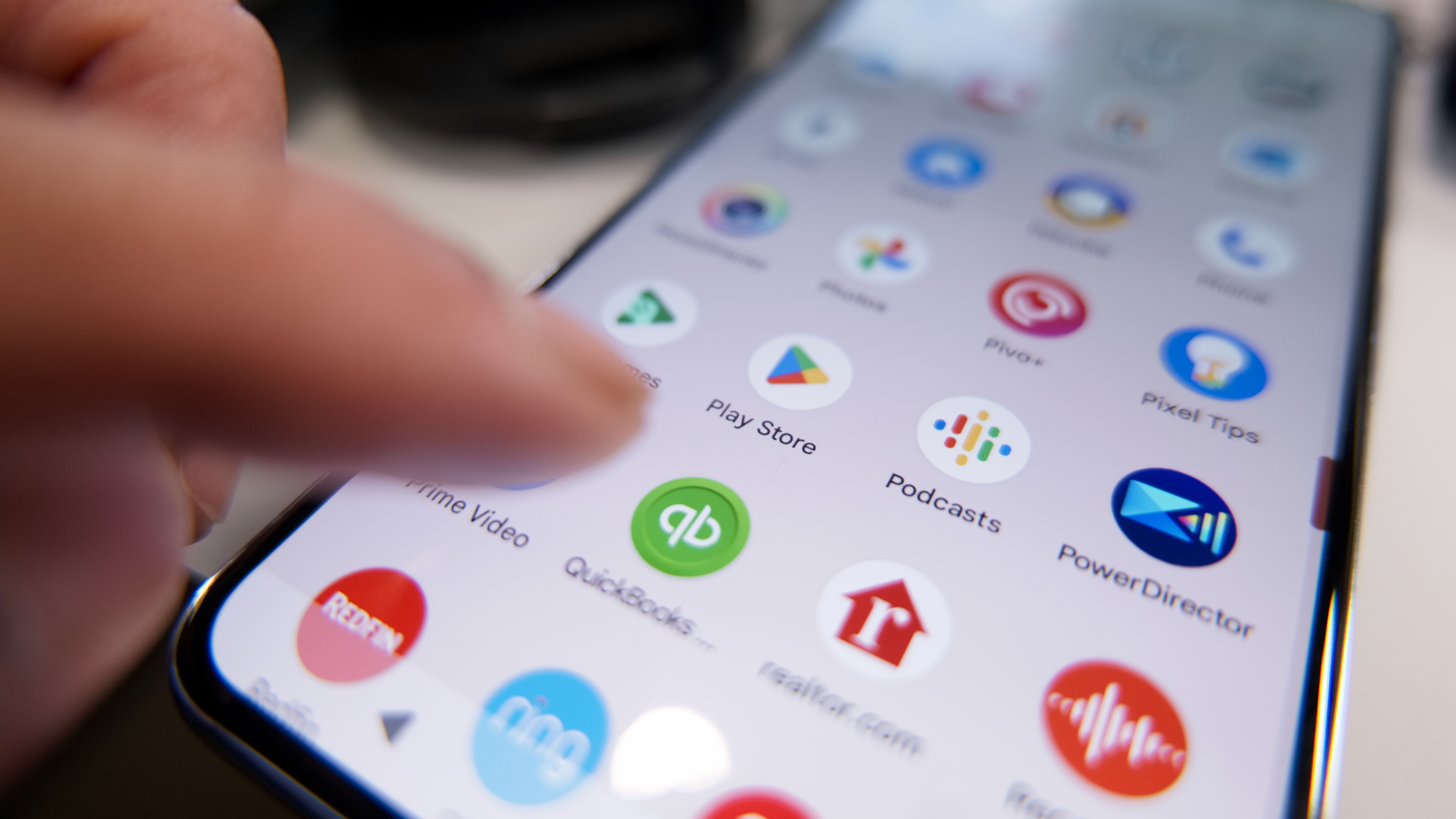 אצבע עומדת ללחוץ על אפליקציית Google Play בטלפון אנדרואיד.