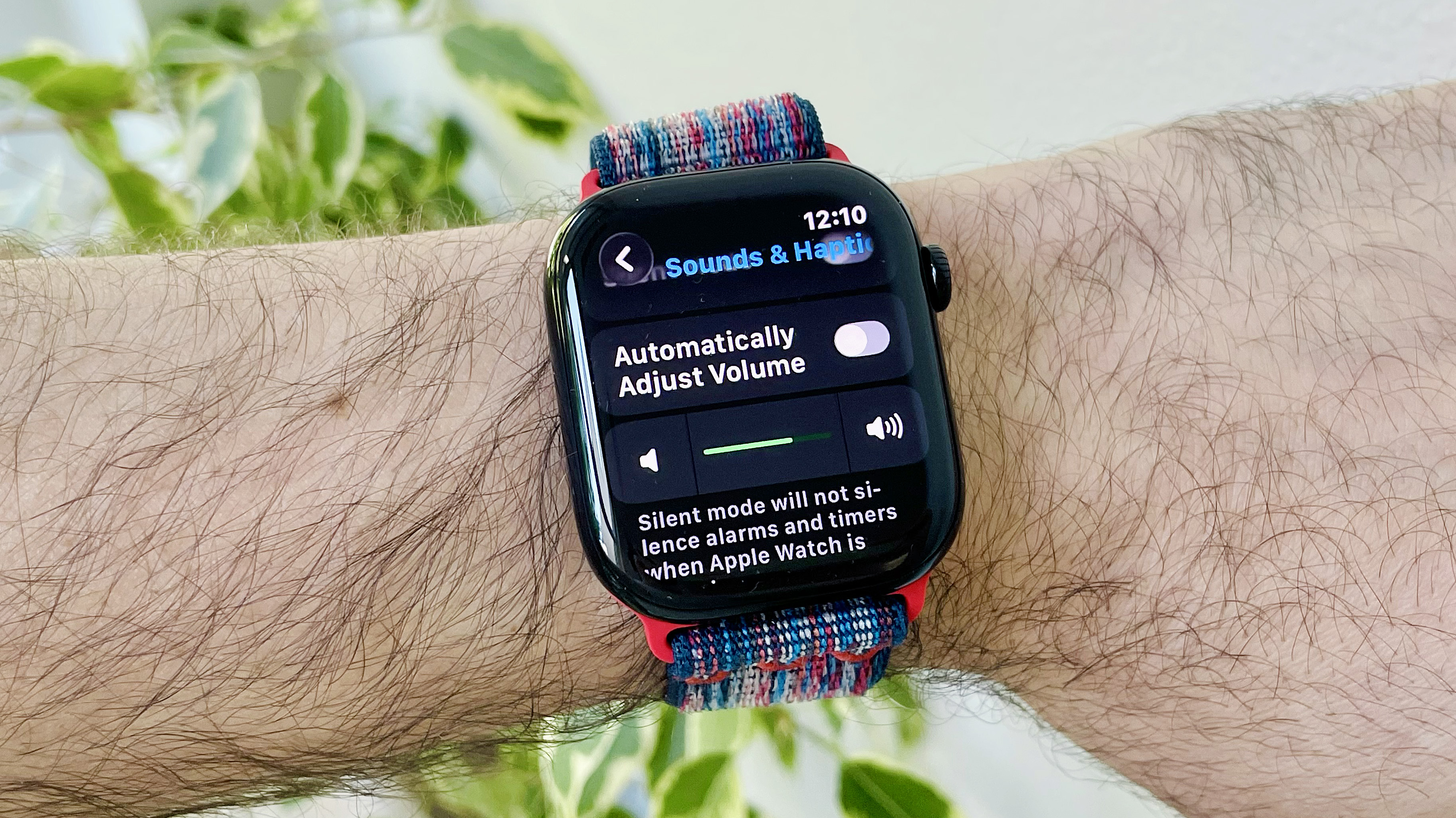 מקרוב של פרק כף היד של המשתמש לובש את Apple Watch Series 10 שמריץ את התוכנה האחרונה של WatchOS 26. המסך מציג את הגדרת התאמות האודיו האוטומטיות החדשות