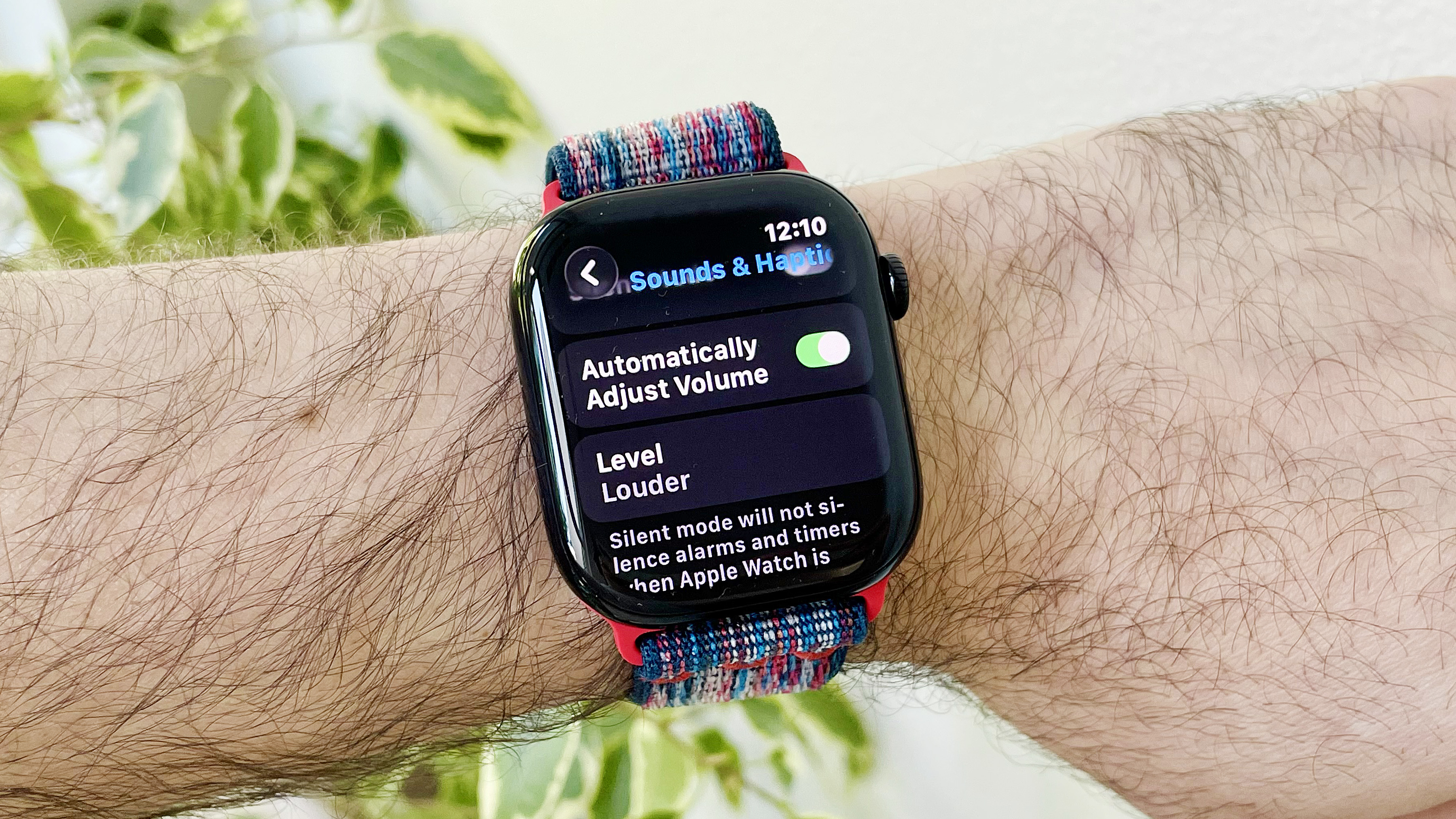 מקרוב של פרק כף היד של המשתמש לובש את Apple Watch Series 10 שמריץ את התוכנה האחרונה של WatchOS 26. המסך מציג את הגדרת התאמות האודיו האוטומטיות החדשות