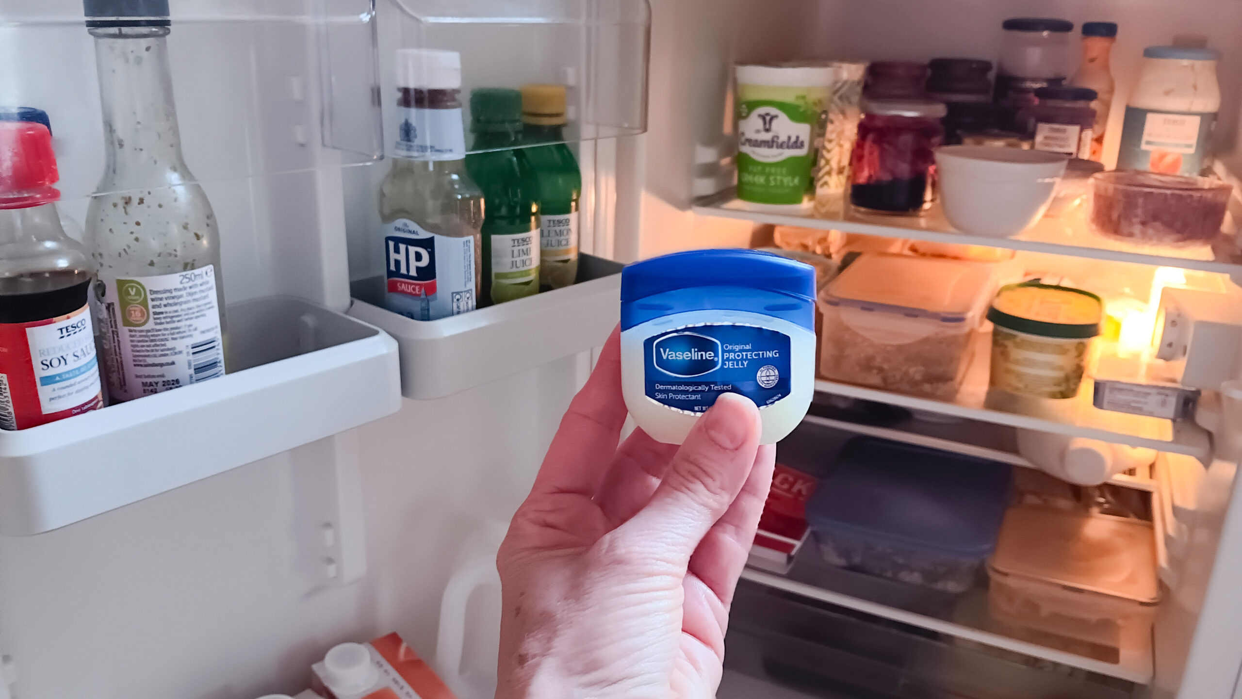 Vaseline being held in front of refrigerator