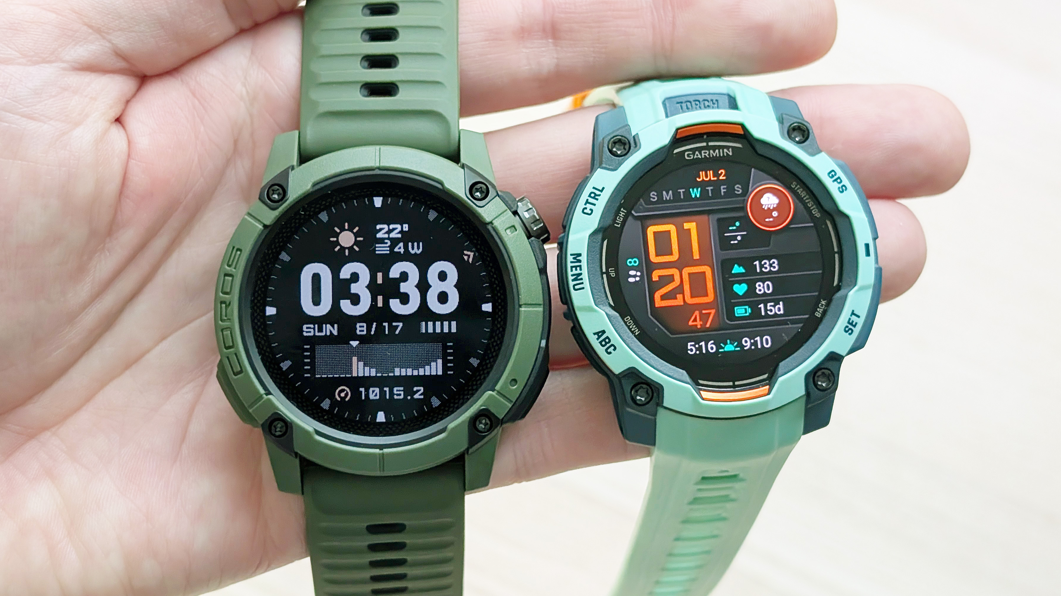 מקרוב של Coros Nomad ו- Garmin Instinct 3 ביד של משתמש