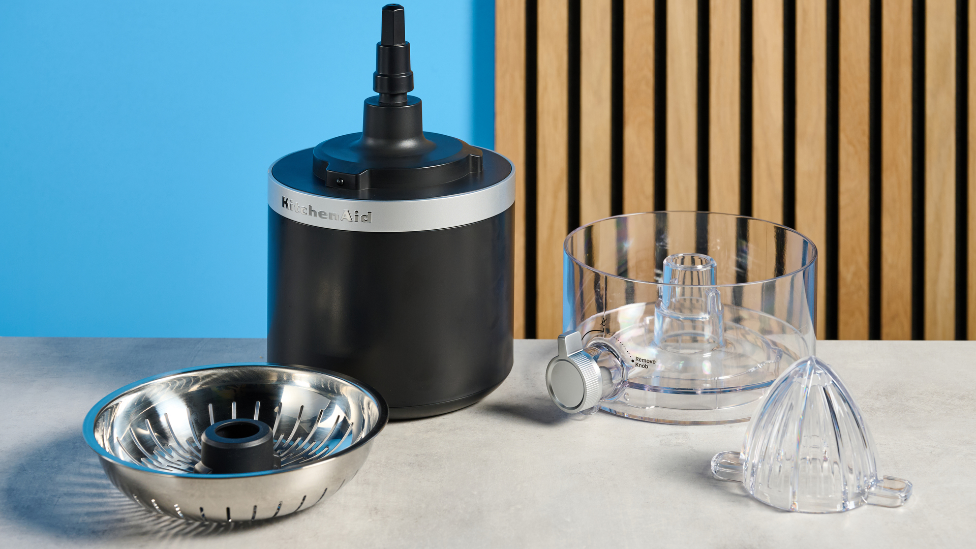 KitchenAid Go מסחטת הדרים חסרת אלחוט בשחור מט שצולם מול רקע כחול.