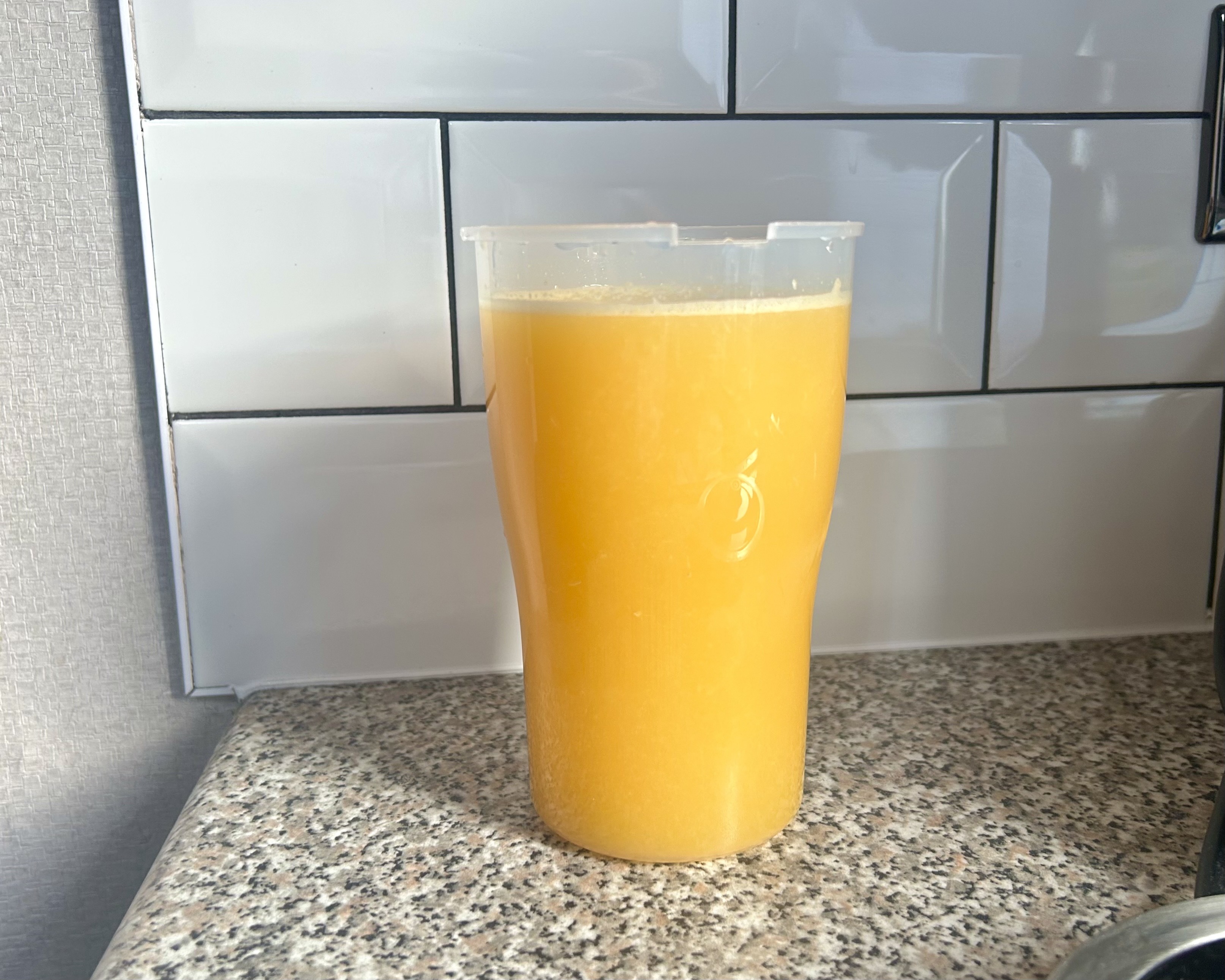 מיץ תפוזים טרי בכוס המיוצר באמצעות KitchenAid Go מסחטת הדרים חסרת אלחונית.