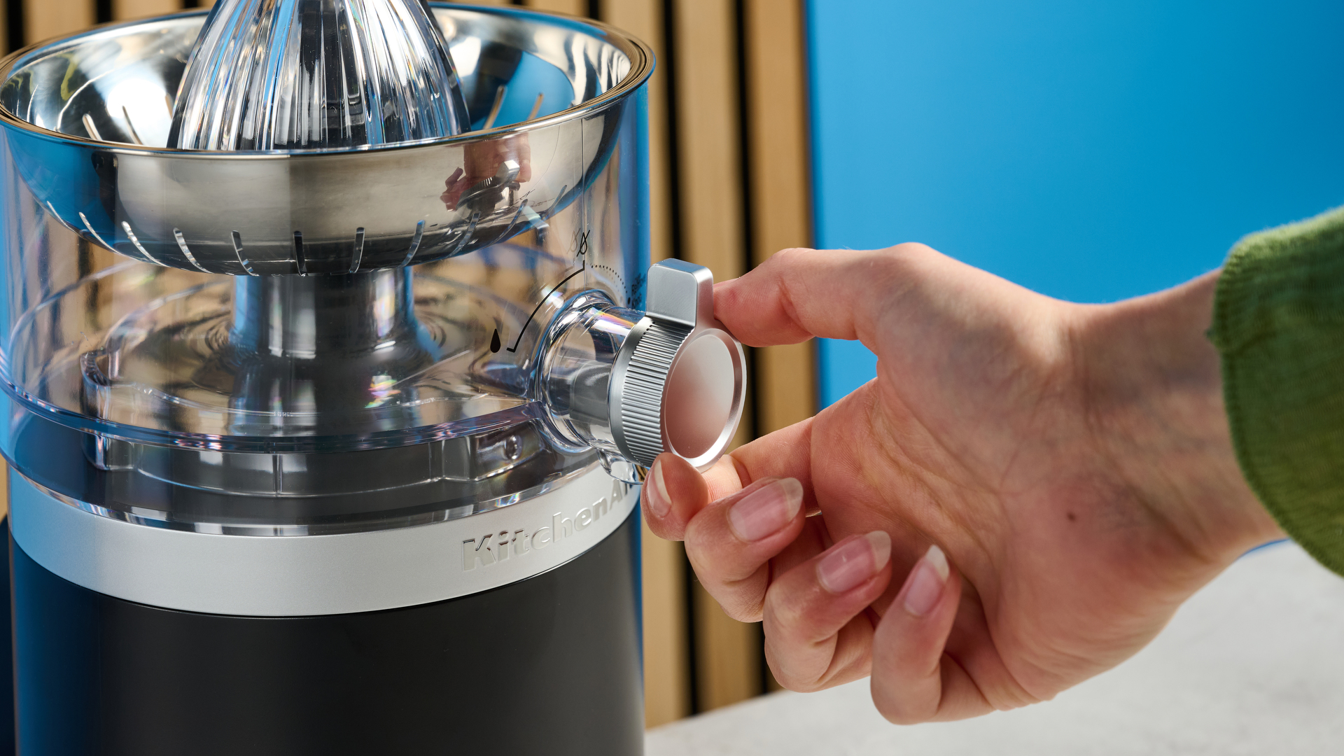 KitchenAid Go מסחטת הדרים חסרת אלחוט בשחור מט שצולם מול רקע כחול.