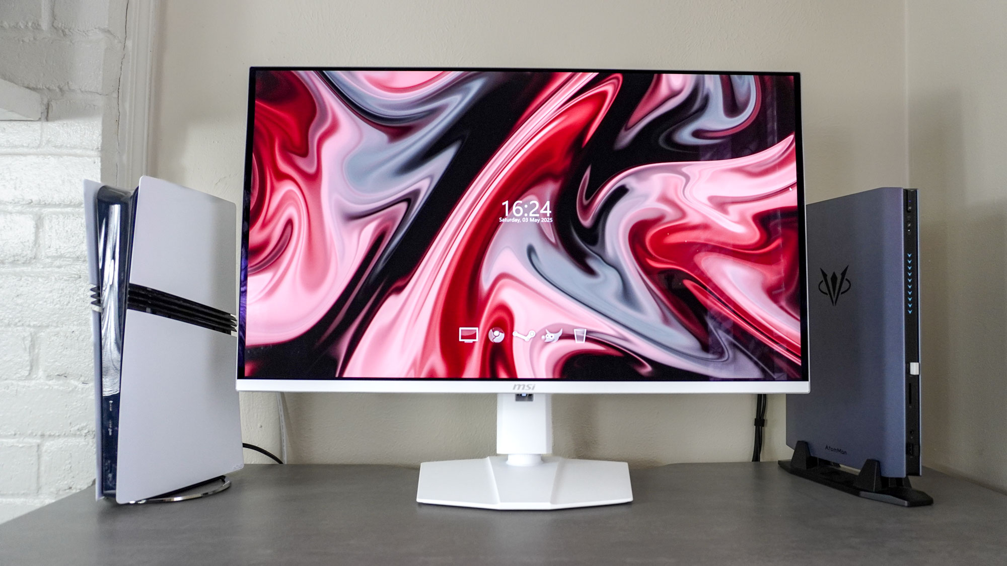 MSI MPG 321URXW QD-oled Monitor על שולחן העבודה ליד PS5 Pro ו- Atomman G7 Ti Mini Gaming PC