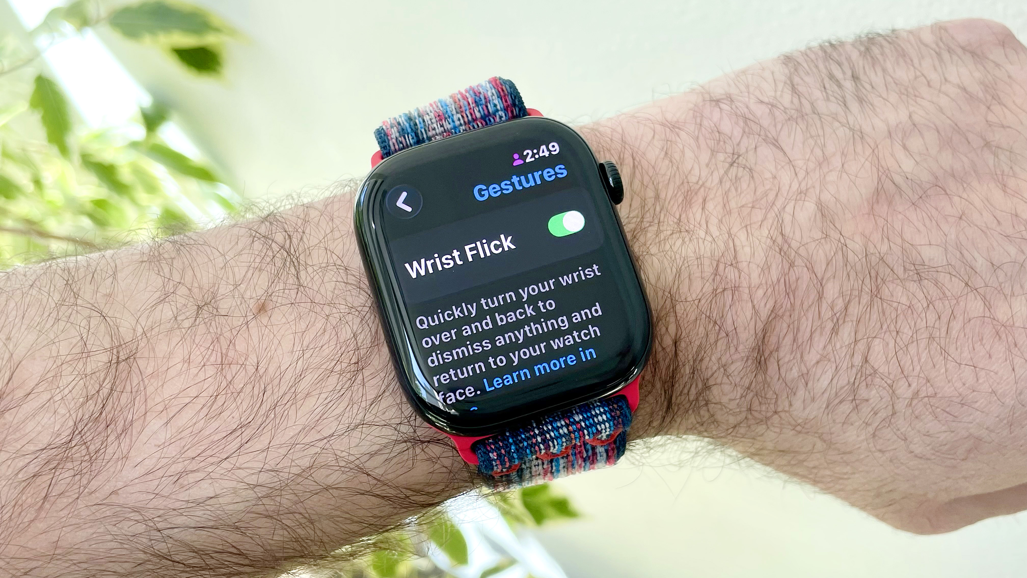 מקרוב של Apple Watch 10 בפרק כף היד של המשתמש המציג את אפשרות התפריט להפעיל את מחוות פליק הפרק החדש ב- WatchOS 26