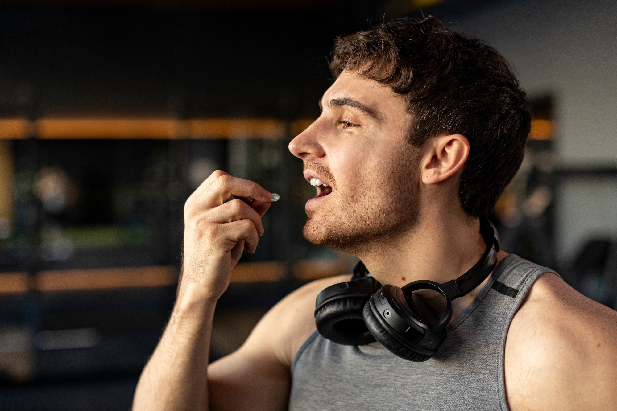Sportive man taking supplement capsule,