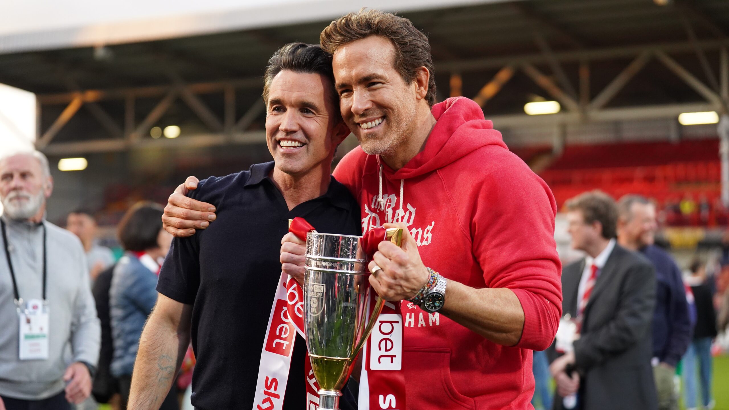 Rob McElhenney and Ryan Reynolds, co-owners of Wrexham AFC, pose for a photo with the trophy following the club's promotion to the Sky Bet Championship during the Sky Bet League One match between Wrexham AFC and Charlton Athletic FC at Racecourse Ground on April 26, 2025 in Wrexham, Wales.