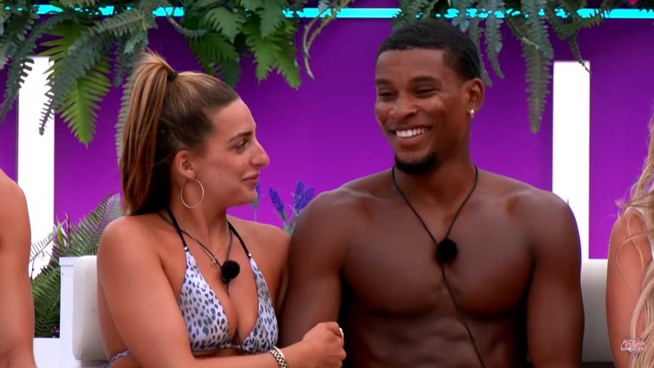 One of the villa's favorite couples, Vegas pool girl Toni sits arm-in-arm with model and dancer Cach Mercer during a game of Couple Goals around the firepit in a screenshot from "Love Island U.K" season 12.