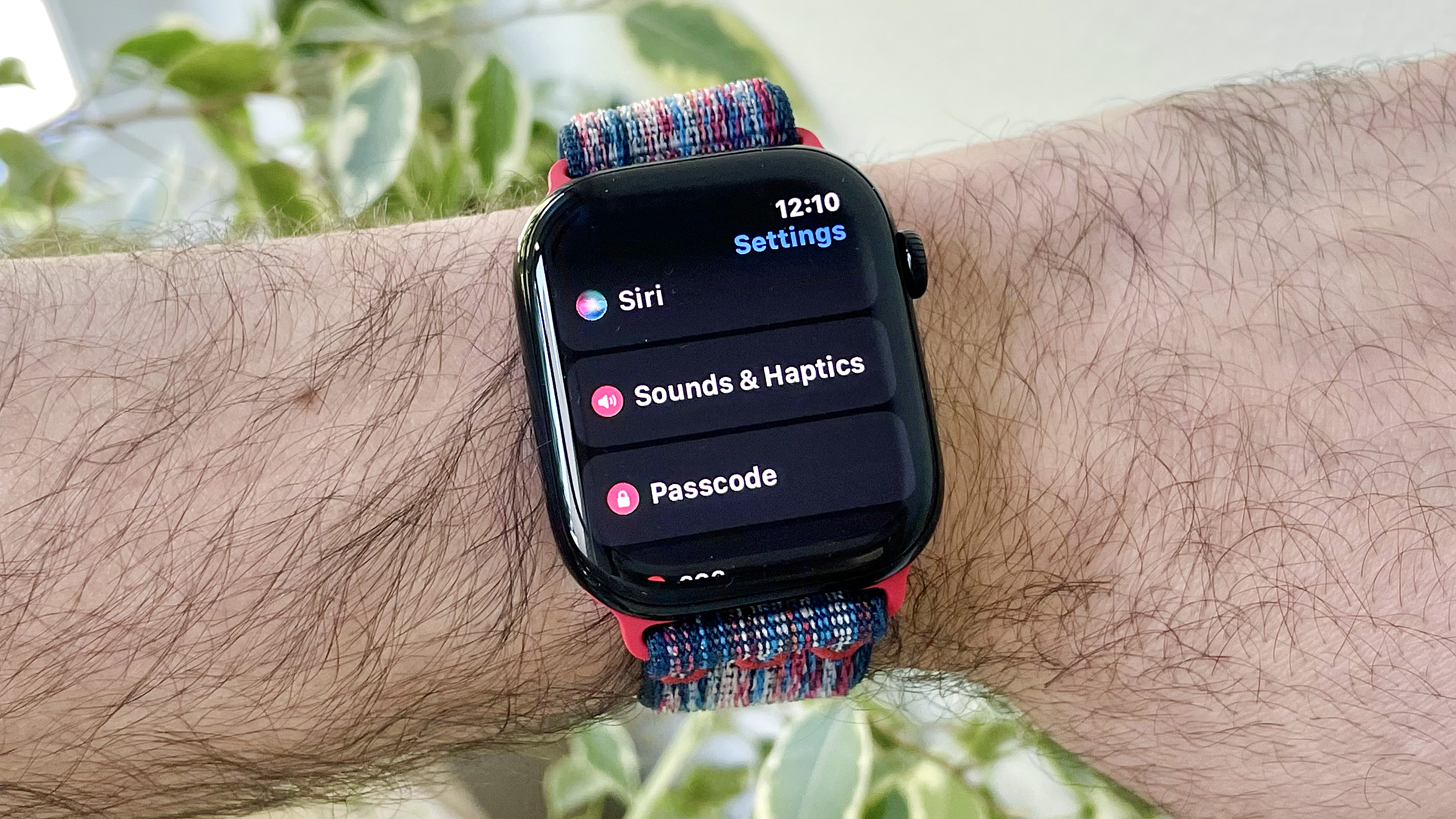 מקרוב של פרק כף היד של המשתמש לובש את Apple Watch Series 10 שמריץ את התוכנה האחרונה של WatchOS 26. המסך מציג את הגדרת התאמות האודיו האוטומטיות החדשות