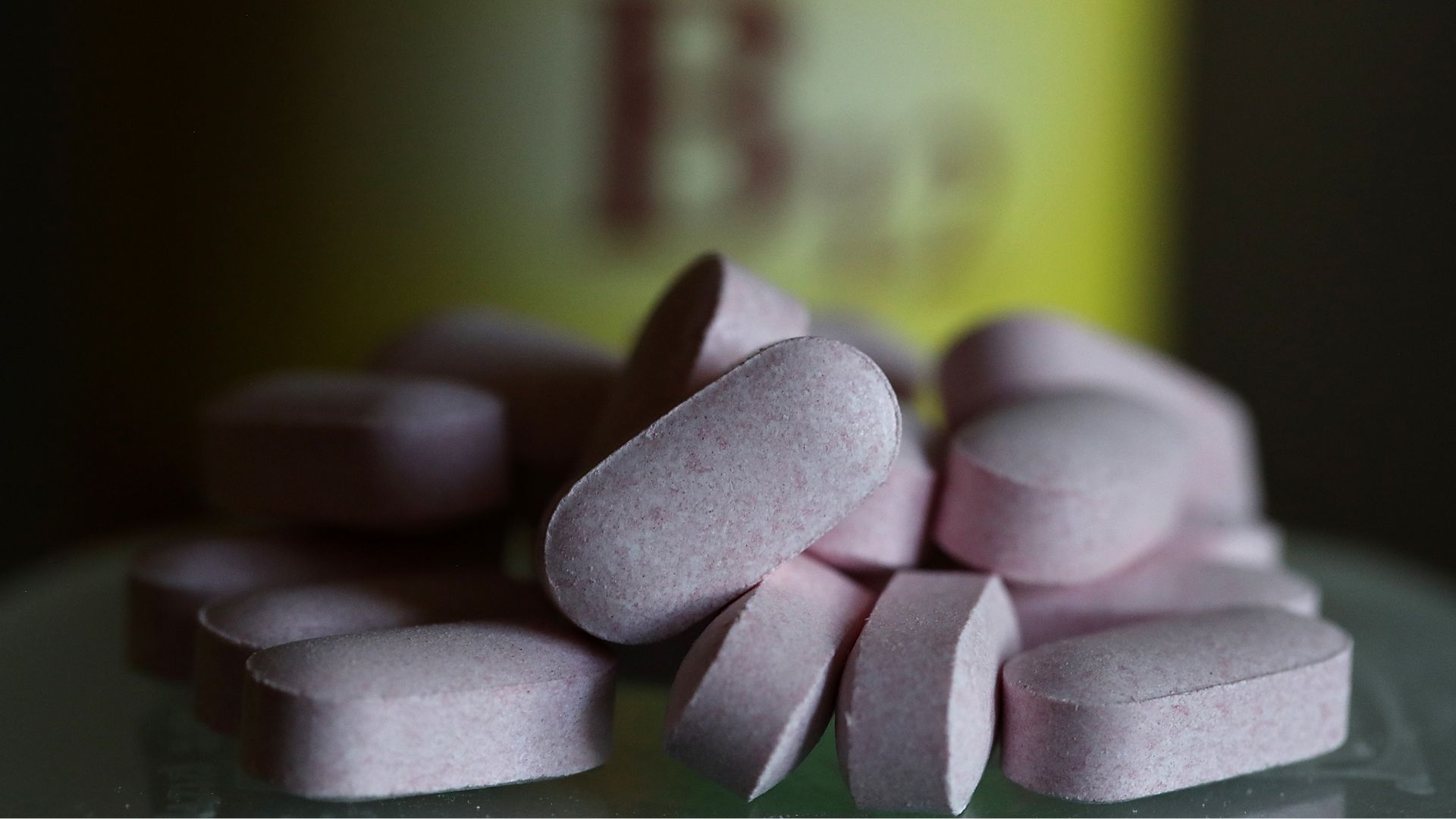 ערימה של ויטמינים B12 מול בקבוק תוסף מחוץ למיקוד עם תווית צהובה שאומרת & quot; B12 & quot ;.