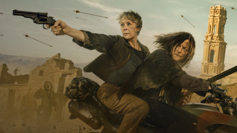 Daryl Dixon (Norman Reedus) riding a motorcycle while Carol Peletier (Melissa McBride) aims a gun at the back in a promotional image for "The Walking Dead: Daryl Dixon" season 3