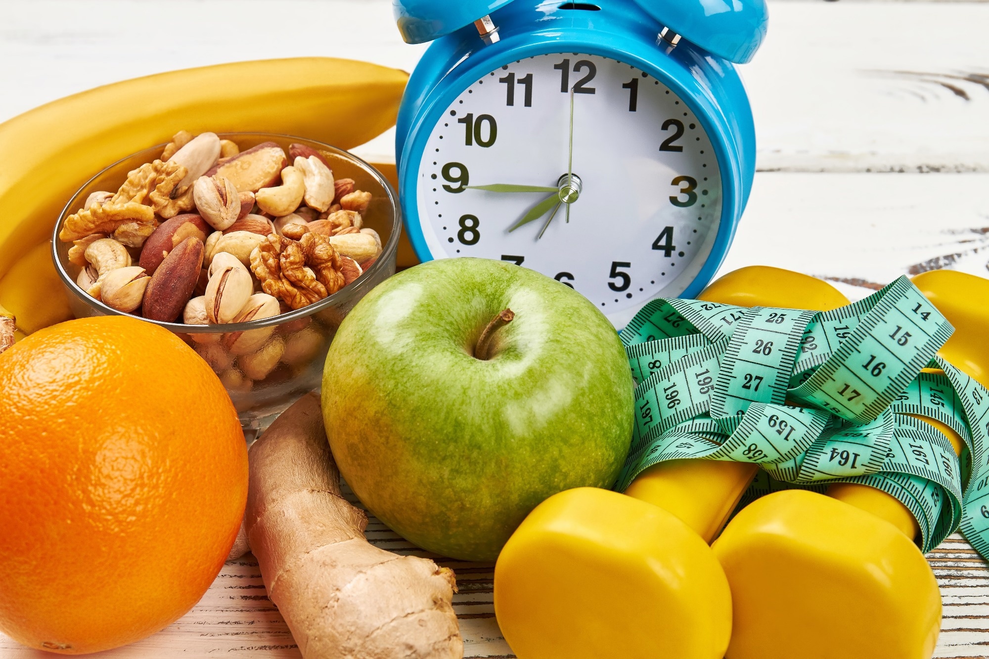 Alarm clock, dumbbells and apple
