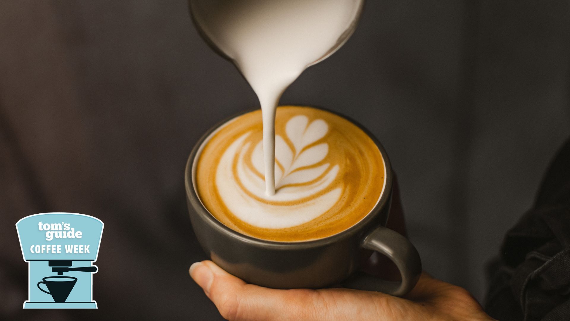A person doing latte art in a black coffee mug