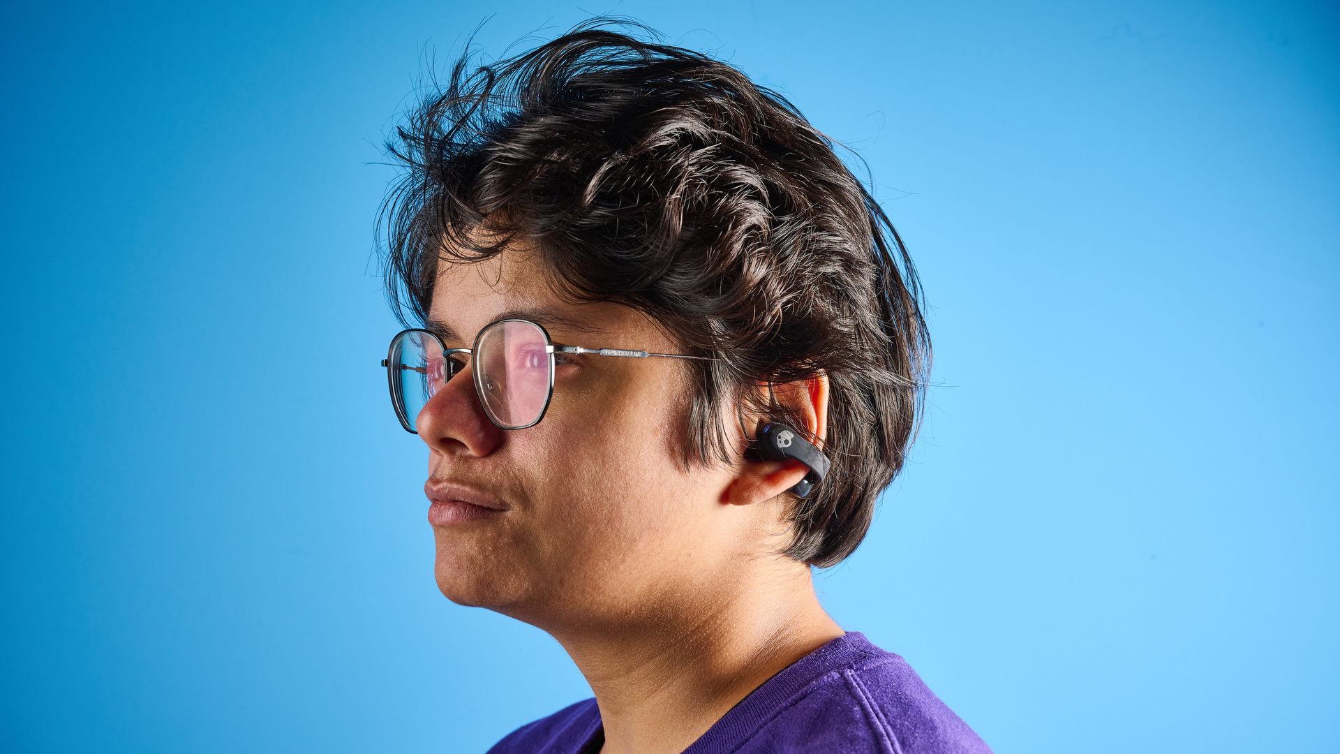 Skullcandy Push 720 פתוח בצבע שחור וכסף עם נרתיק טעינה מצולם על רקע כחול