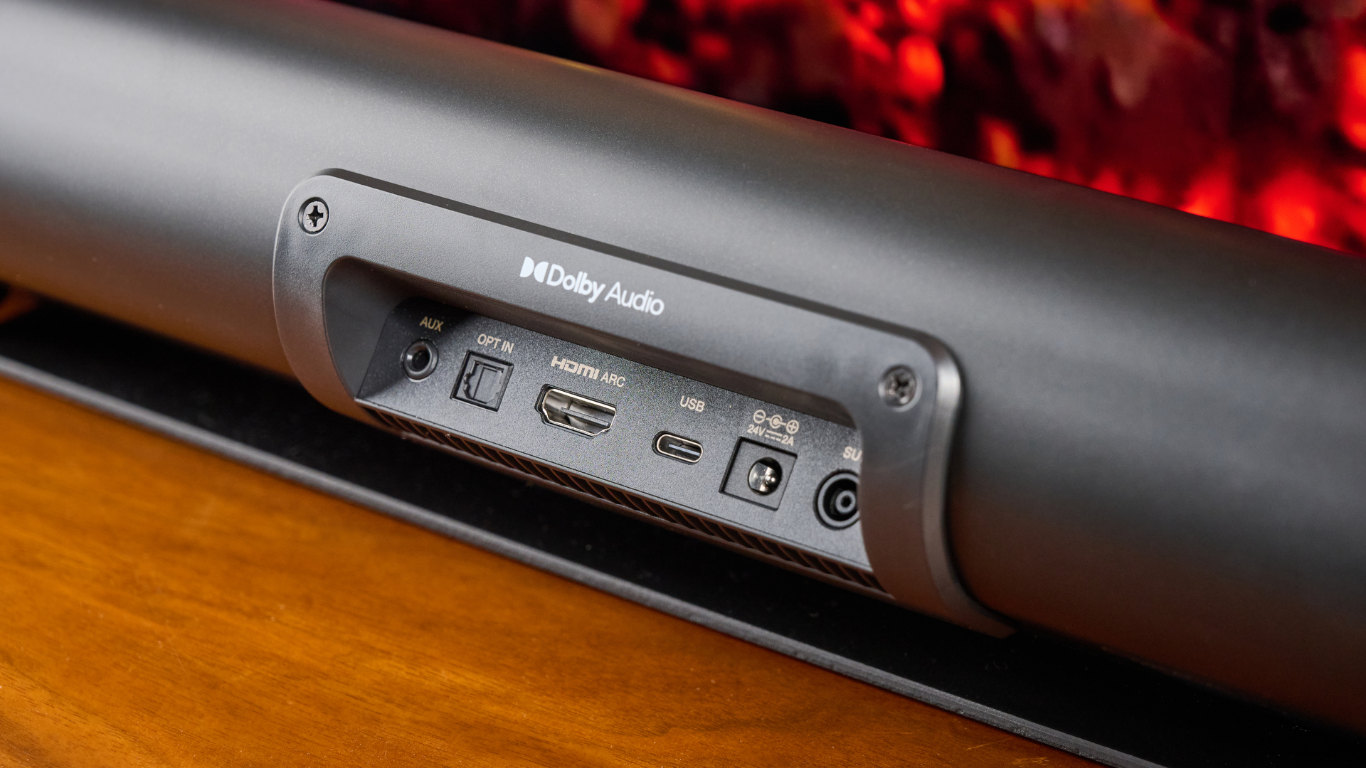 סרגל הסאונד והסאבוופר היצירתי של stage pro, מערכת קולנוע ביתי בתקציב סופר-תקציבי עם 2.1 ערוצים ושלט רחוק מצולם על מעמד טלוויזיה מעץ עם טלוויזיה מאחור