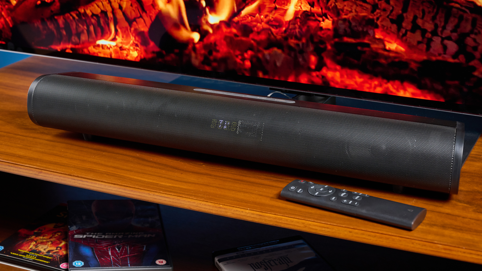 סרגל הסאונד והסאבוופר היצירתי של stage pro, מערכת קולנוע ביתי בתקציב סופר-תקציבי עם 2.1 ערוצים ושלט רחוק מצולם על מעמד טלוויזיה מעץ עם טלוויזיה מאחור