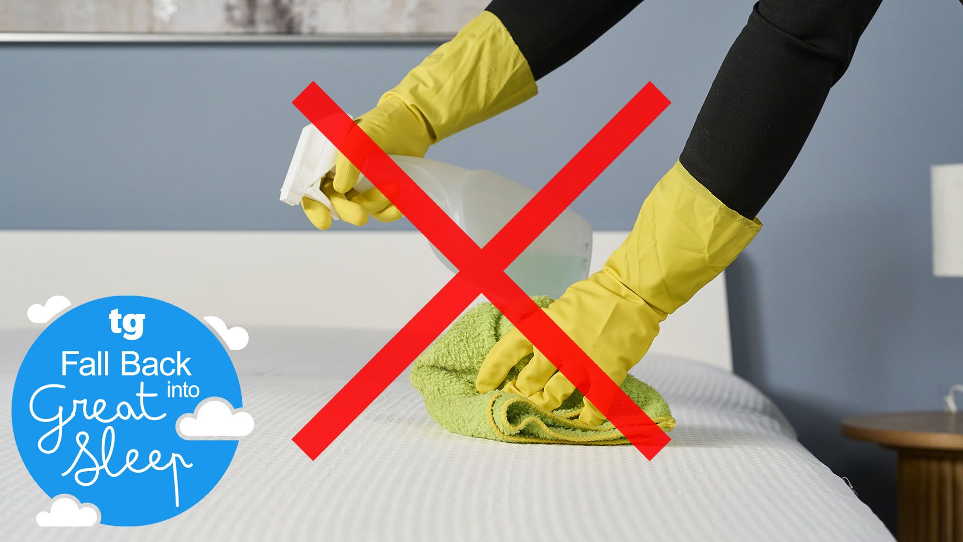 A close up of a pair of hands wearing rubber gloves holding a spray bottle filled with liquid and a microfiber cloth over the surface of a mattress. A red cross sits in the center of the image, on top of the hands and the spray bottle. In the bottom left, a Tom's Guide Fall Back into Great Sleep graphic