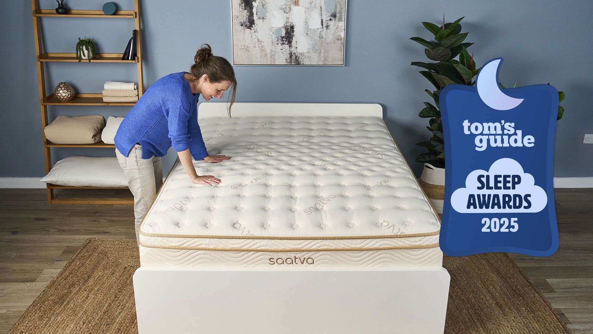 A Saatva Classic mattress in a bedroom, with a woman pressing her hands down on it and a Tom's Guide Sleep Awards 2025 badge overlaid
