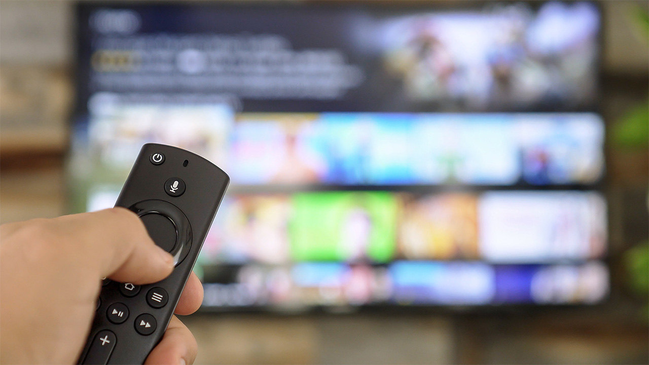 יד מחזיקה שלט לטלוויזיה ומשתמשת בו כדי לגשת לשירות סטרימינג